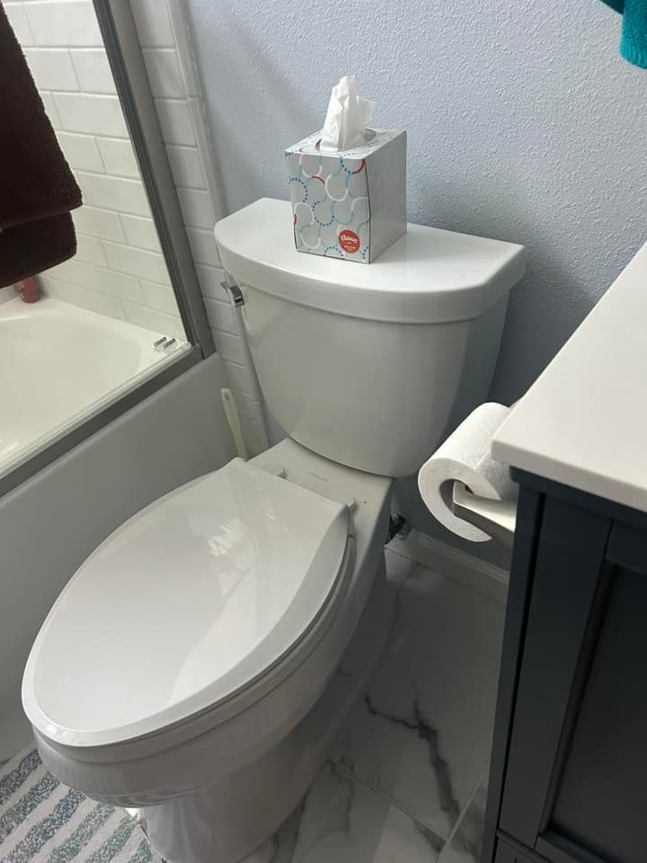 A toilet with a box of tissues on top of it in a bathroom.