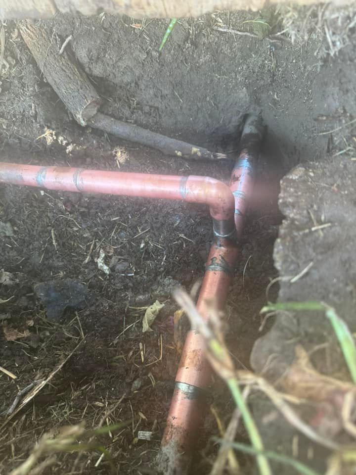 A close up of a copper pipe in the ground.