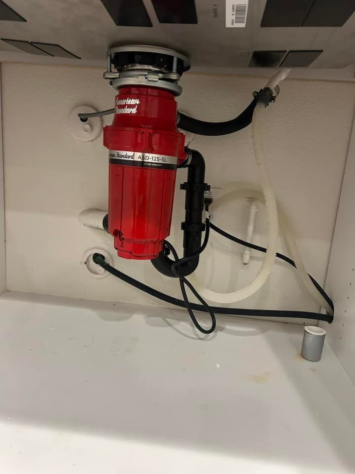 A red garbage disposal is sitting under a sink.