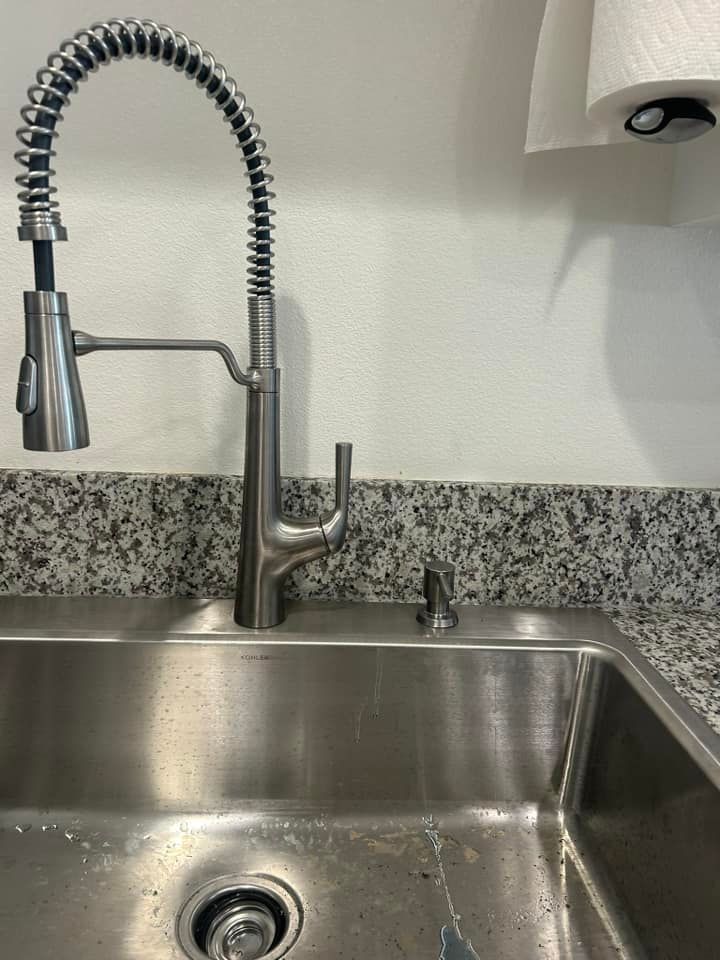 A kitchen sink with a stainless steel faucet and a paper towel holder.