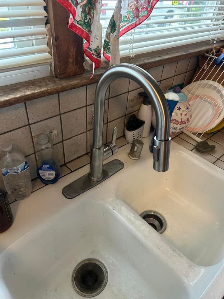 A kitchen sink with a faucet and a window.