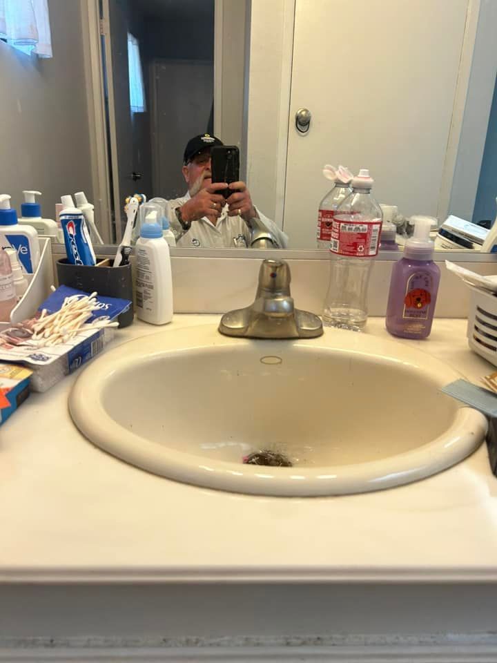 A man is taking a picture of himself in a bathroom sink.