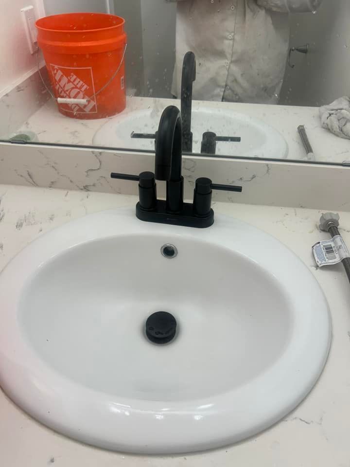 A bathroom sink with a black faucet and a mirror.
