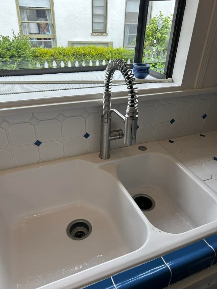 A kitchen sink with a faucet and a window in the background
