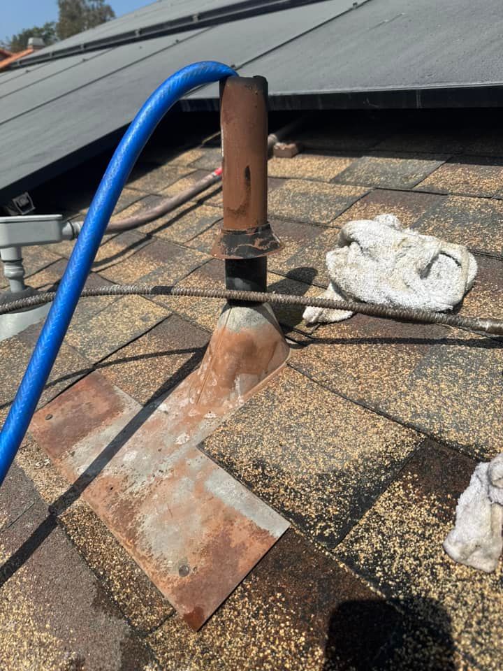 A blue hose is connected to a pipe on a roof.