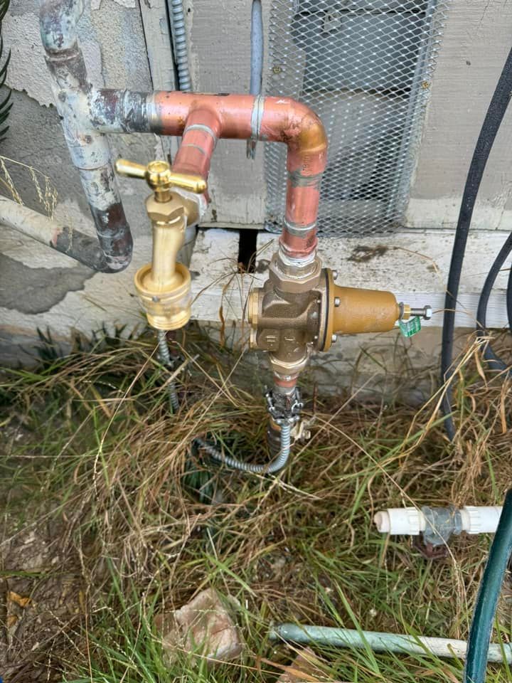 A hose with a valve attached to it is sitting in the grass.