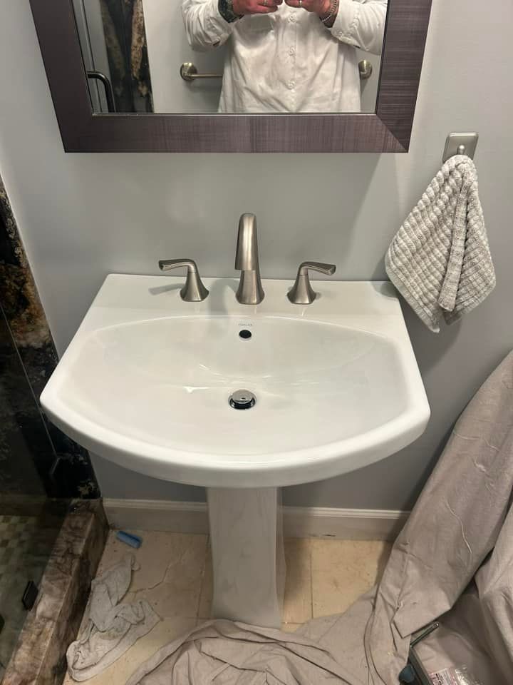 A person is taking a picture of themselves in a bathroom sink.