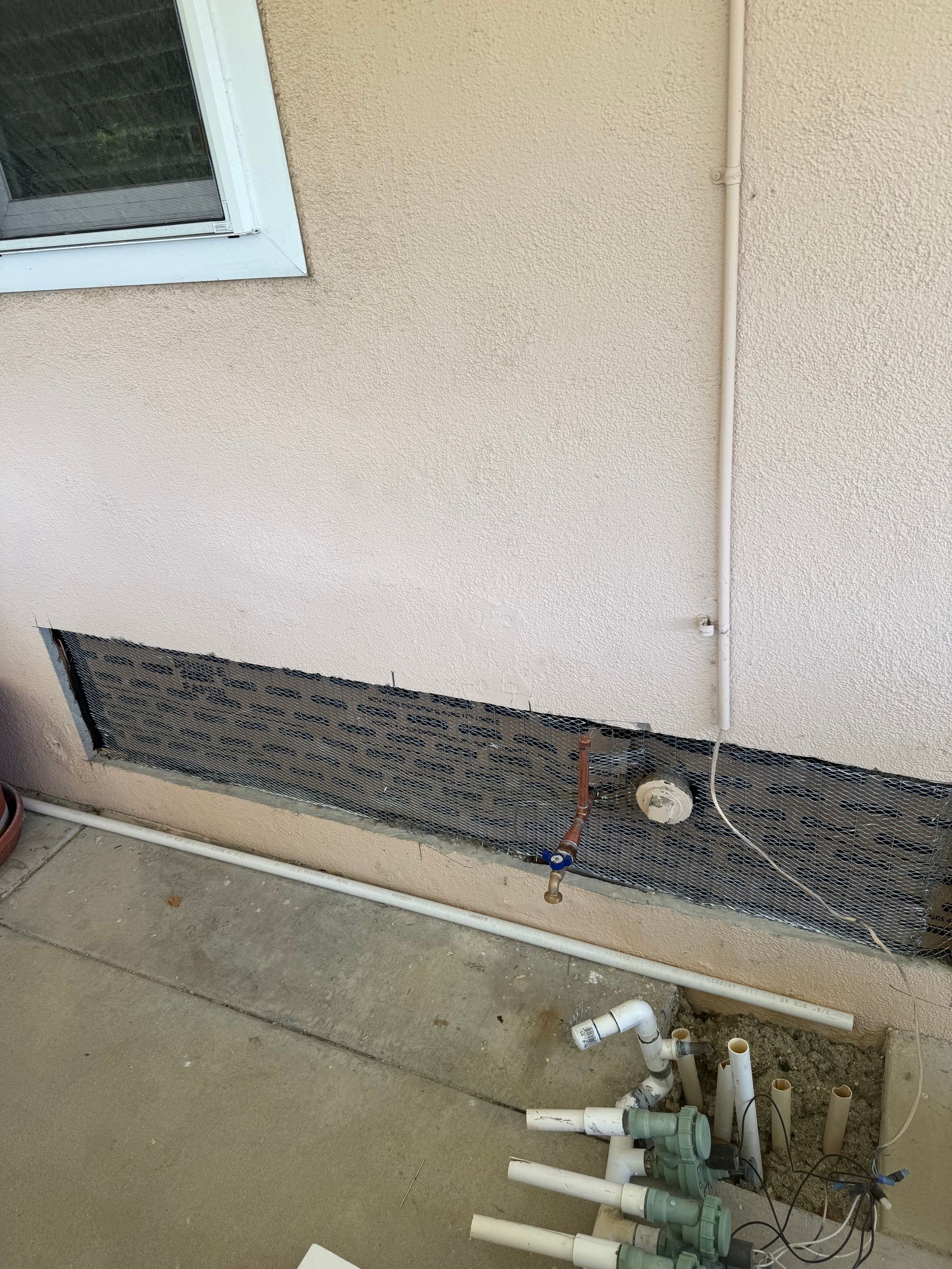 A wall with a hole in it and a bunch of pipes coming out of it.