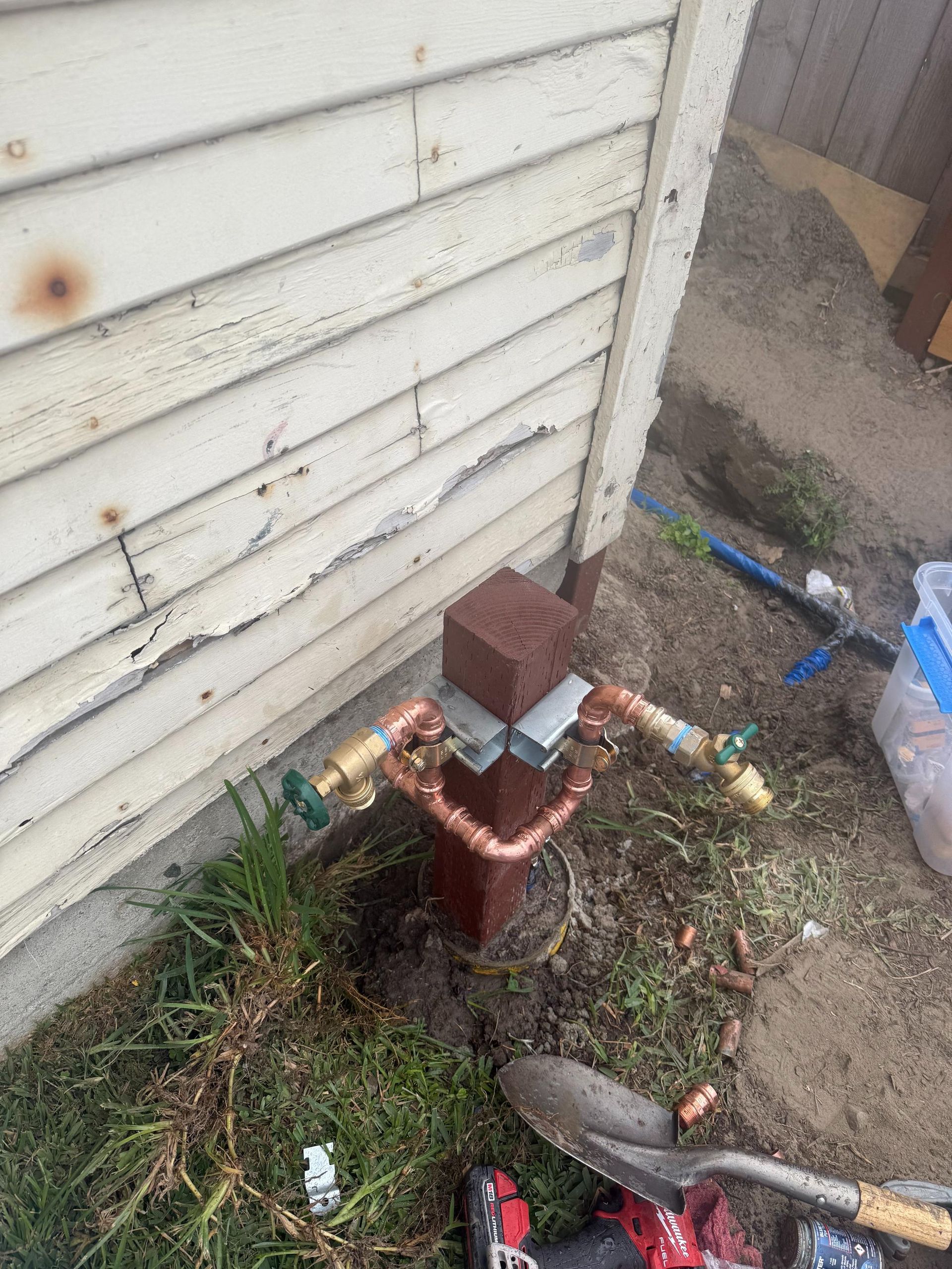 A water hydrant is being installed on the side of a house.