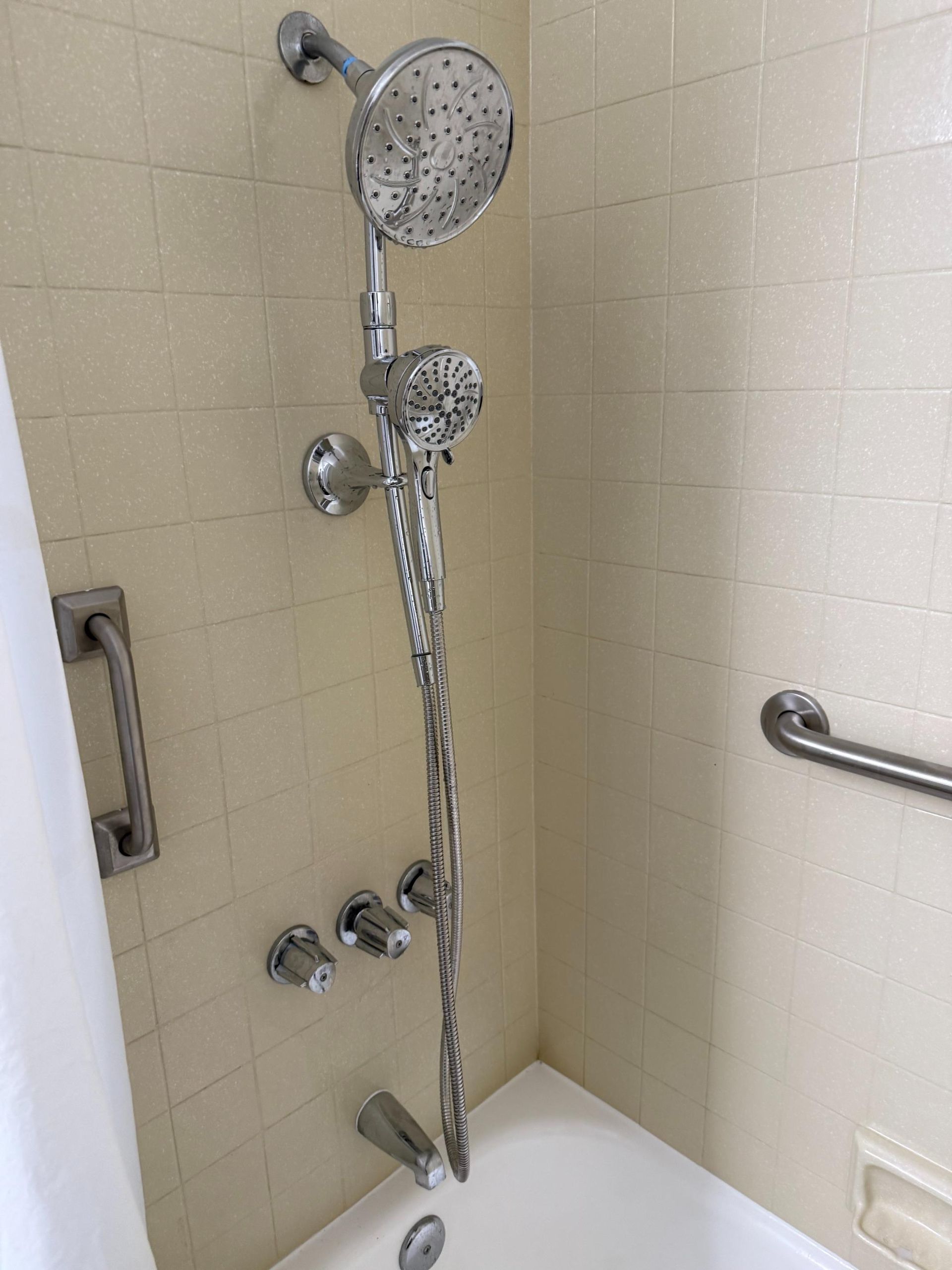 A shower head is hanging over a bathtub in a bathroom.