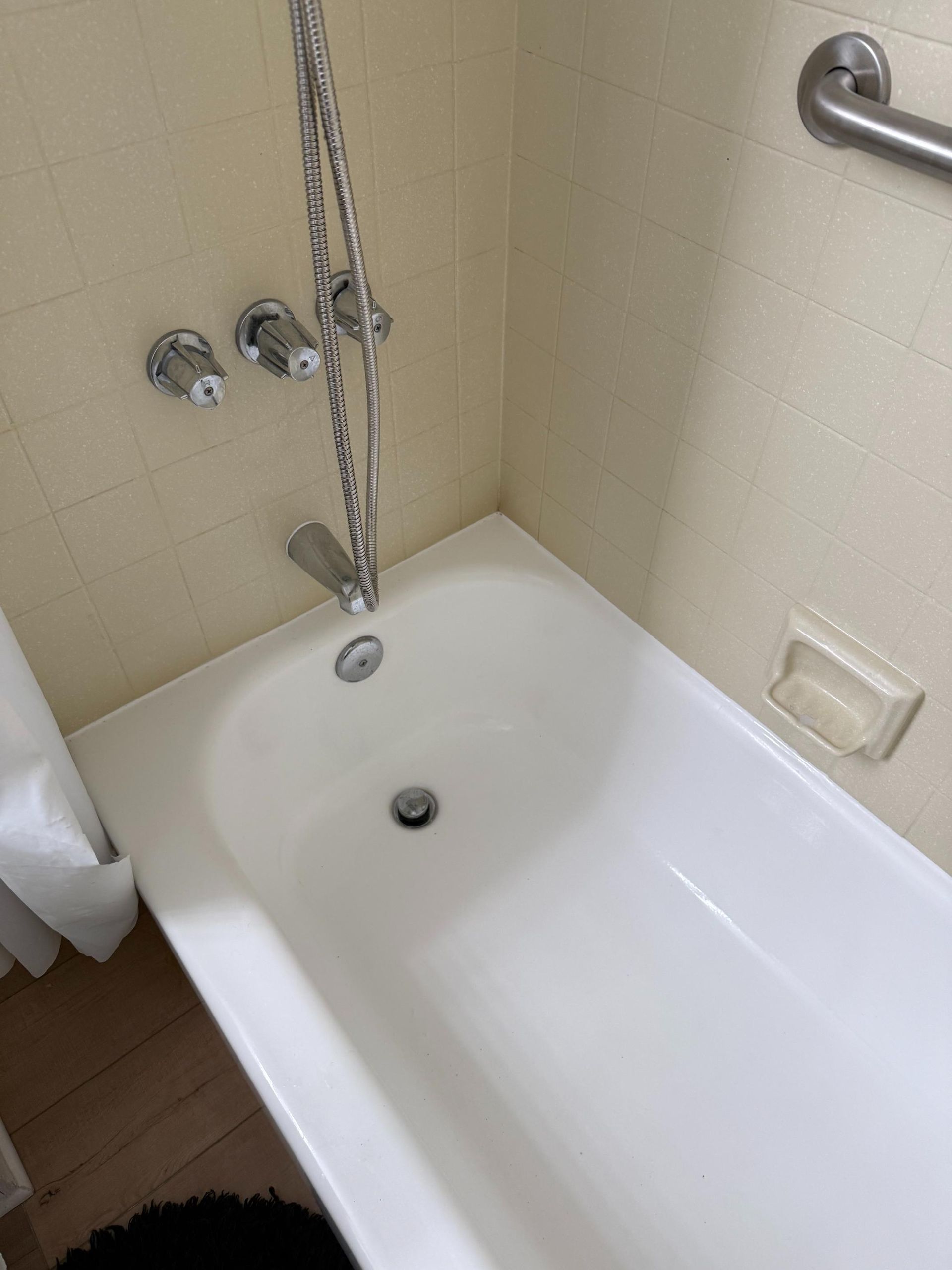 A white bathtub in a bathroom with a shower head.