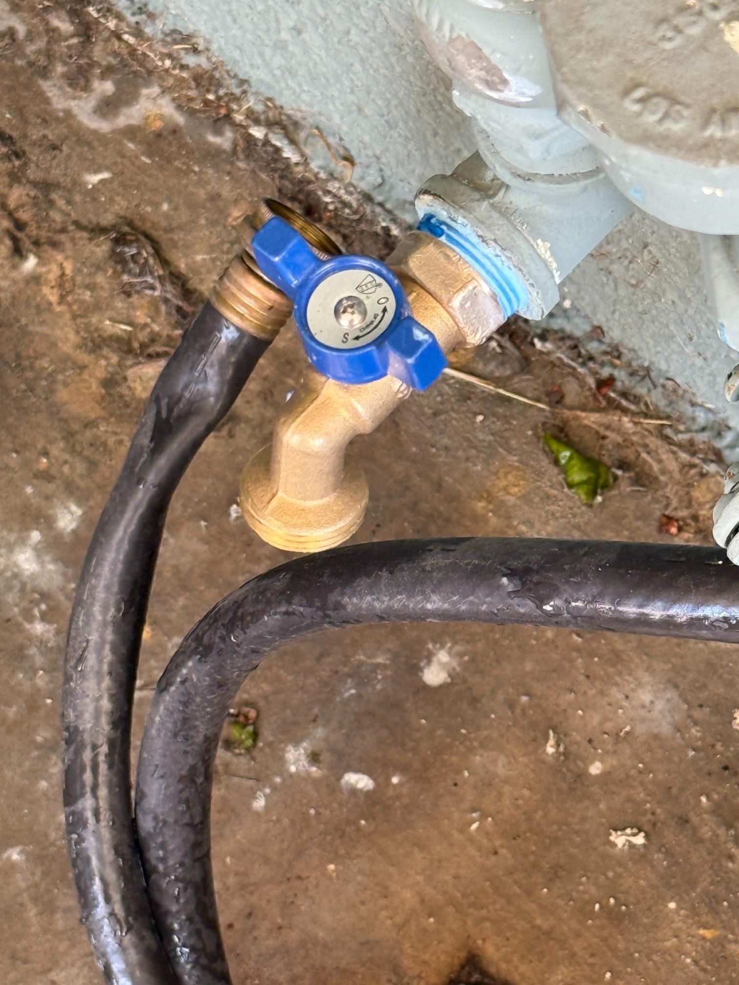 A close up of a hose attached to a faucet on the ground.