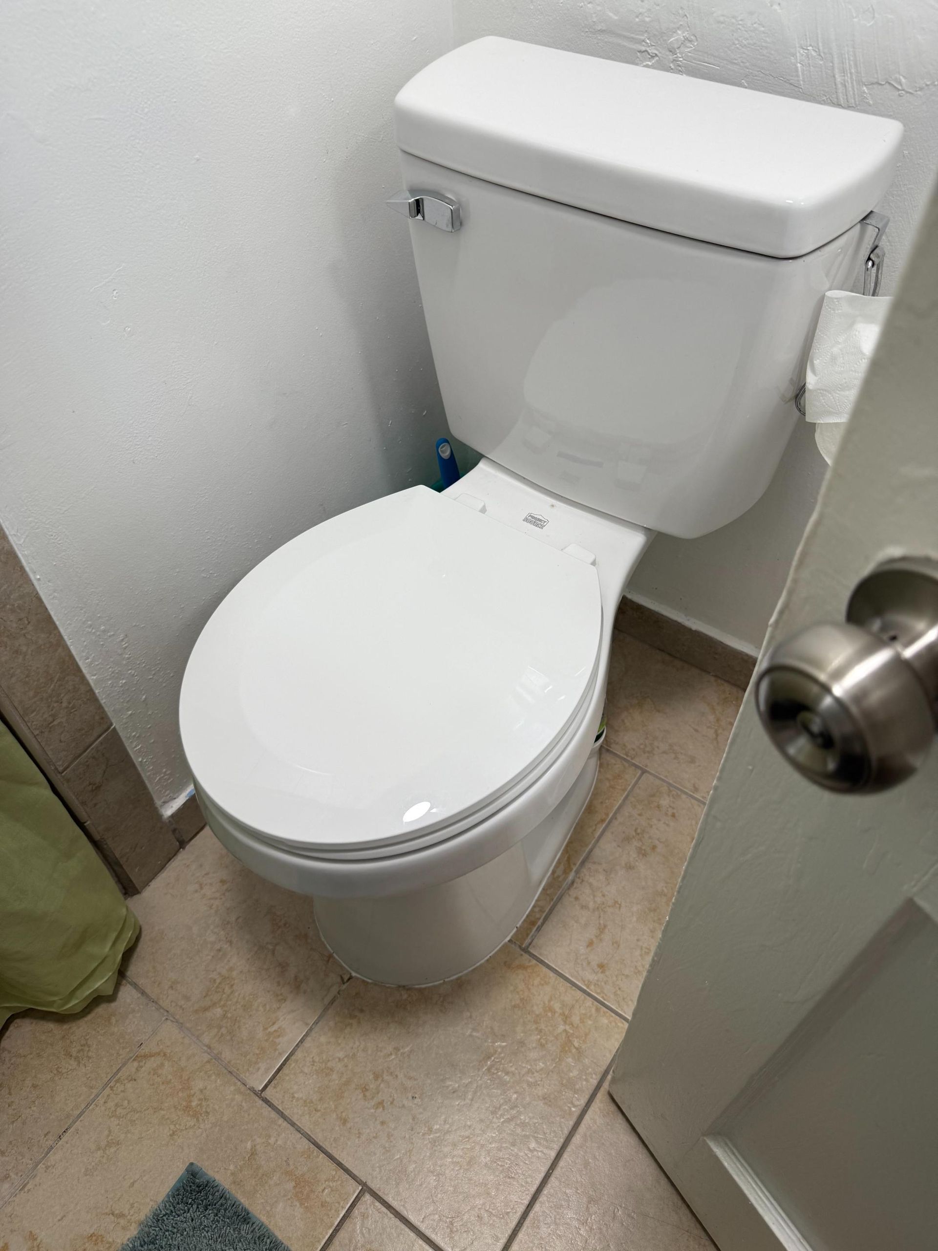 A white toilet is sitting in a bathroom next to a door.