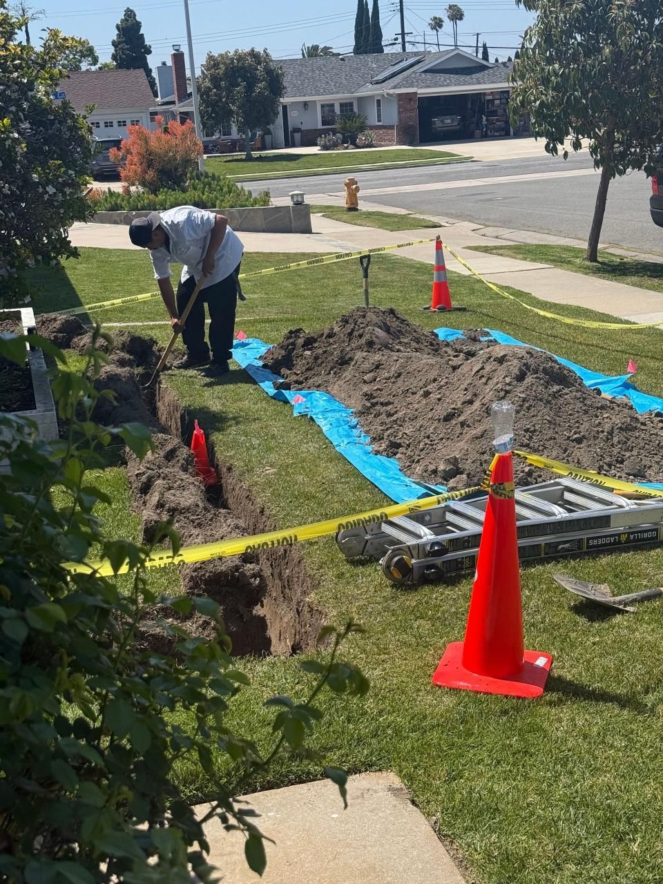 A man is digging a hole in the grass in front of a house.