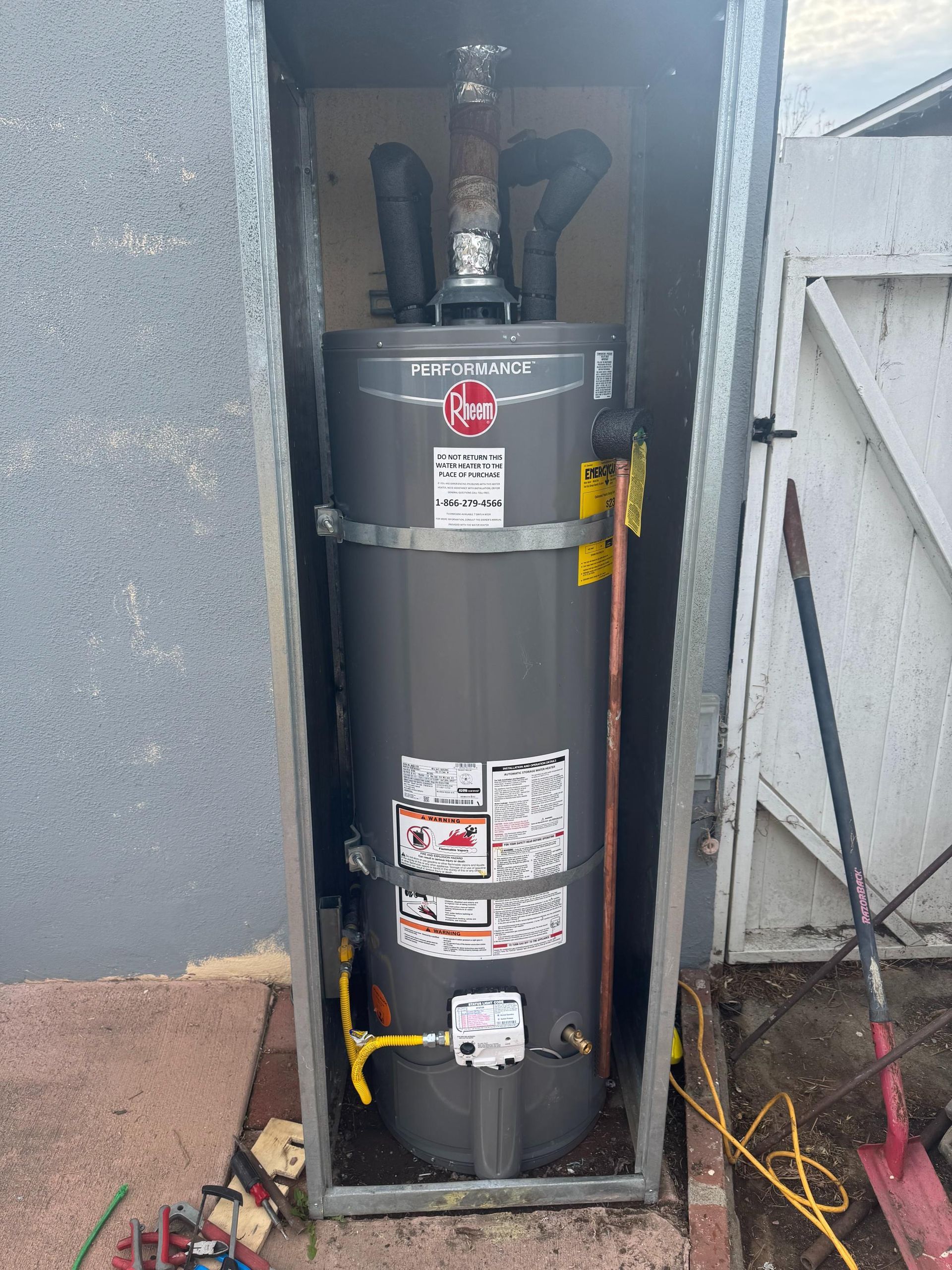 A water heater is sitting inside of a metal box.