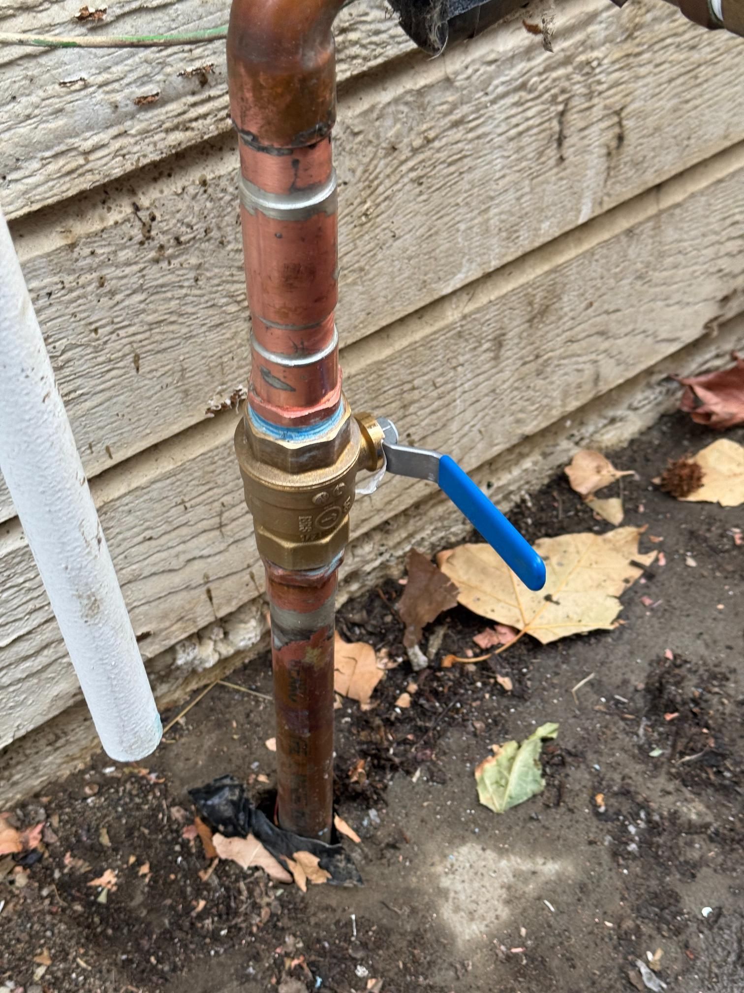 A copper pipe with a blue ball valve attached to it.