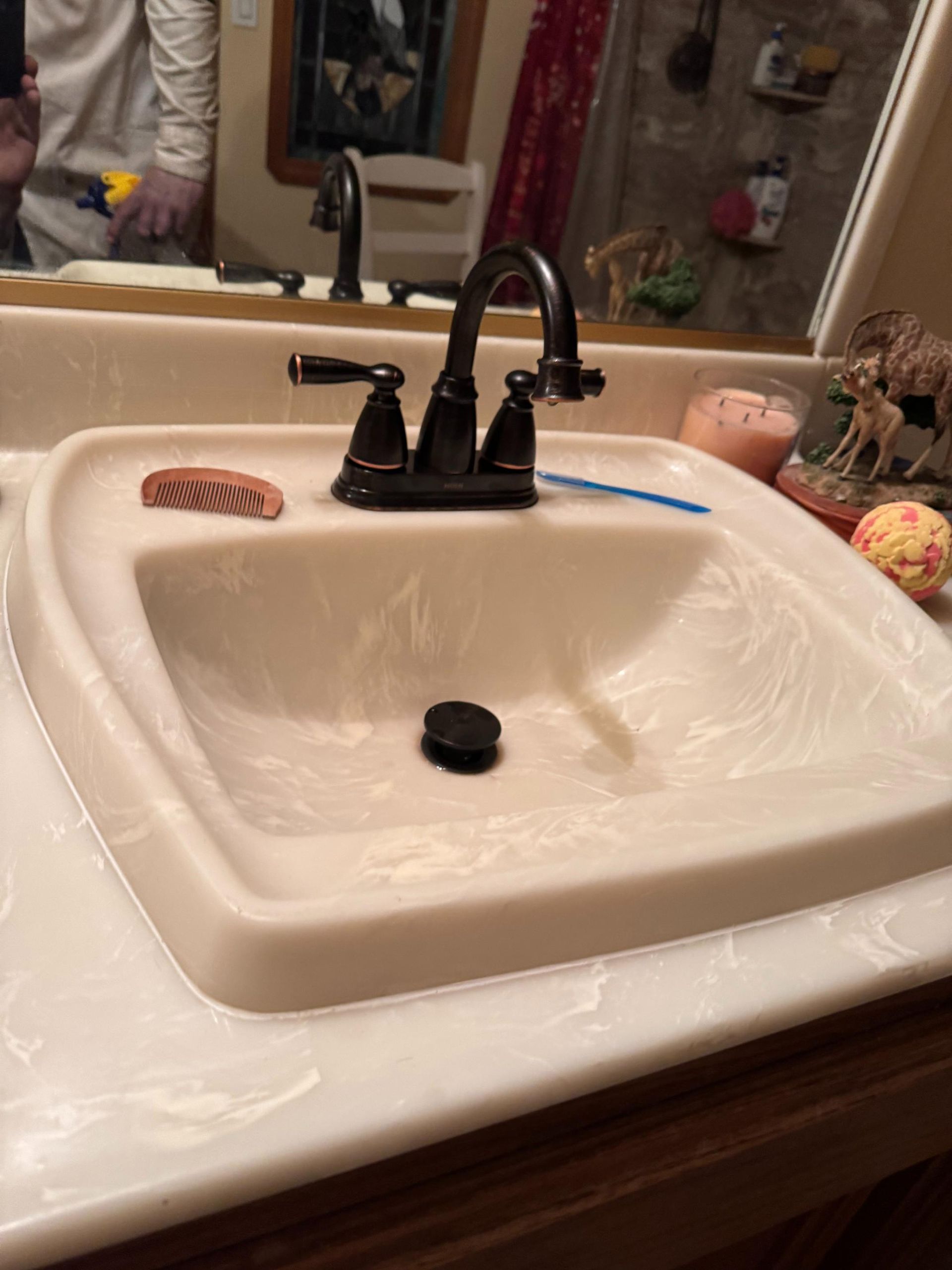 A bathroom sink with a black faucet and a toothbrush in it
