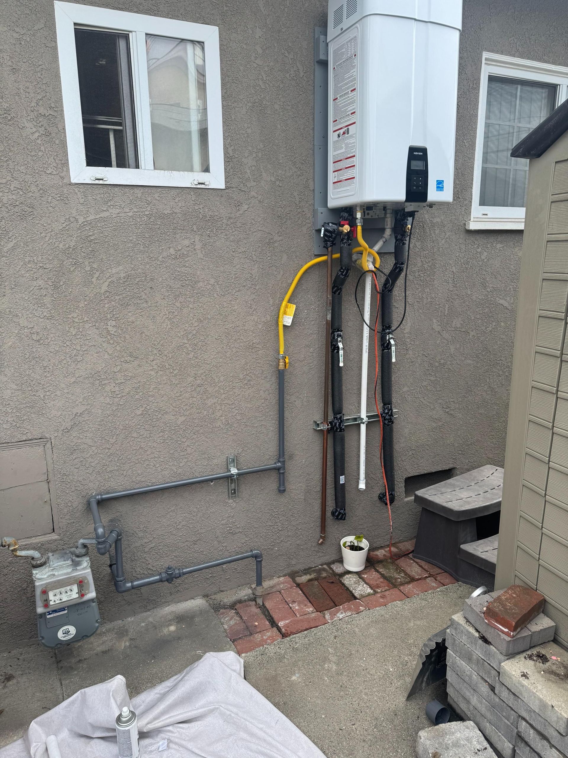 A gas water heater is installed on the side of a house.