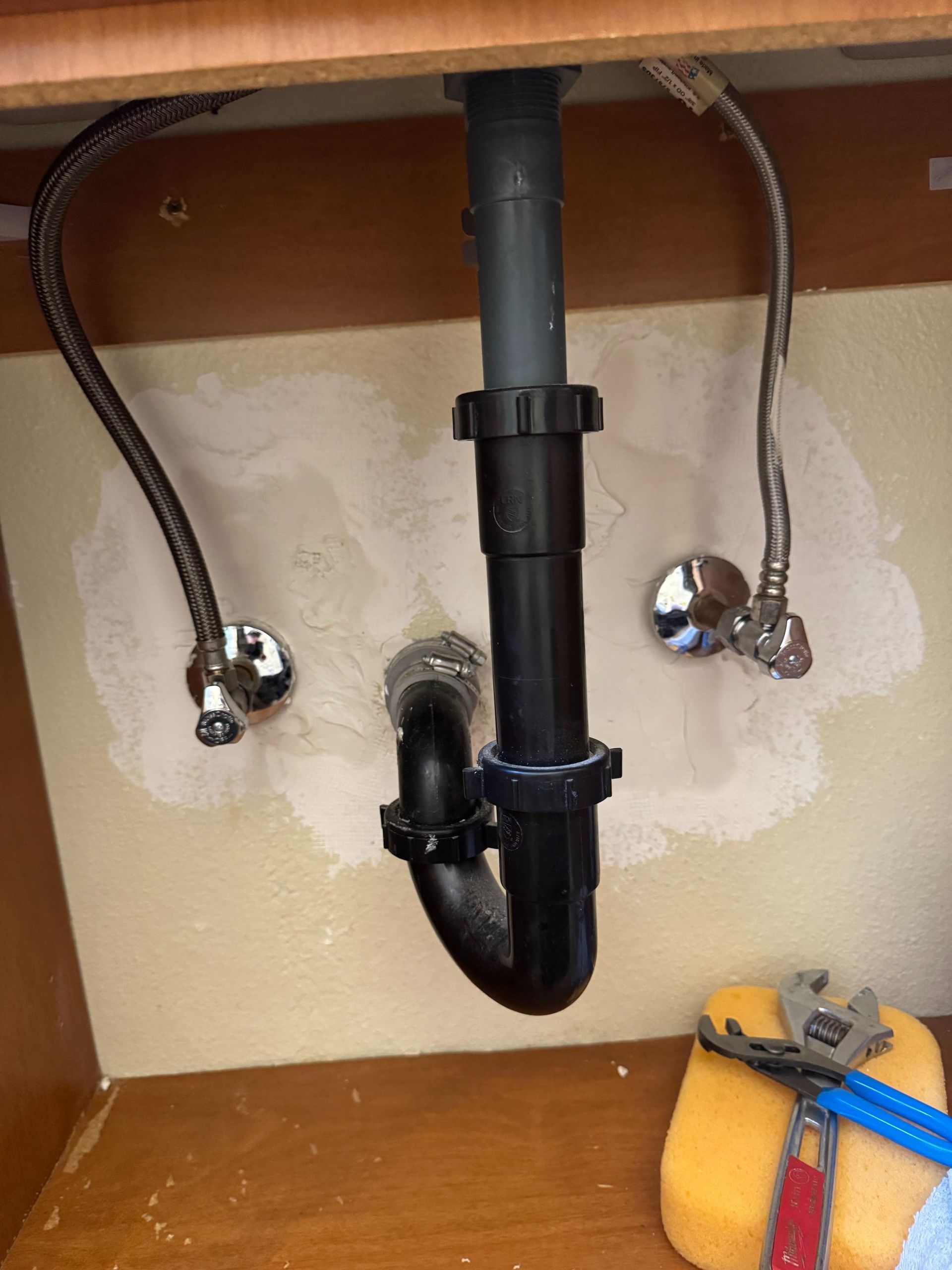 A sink with a plumbing pipe underneath it