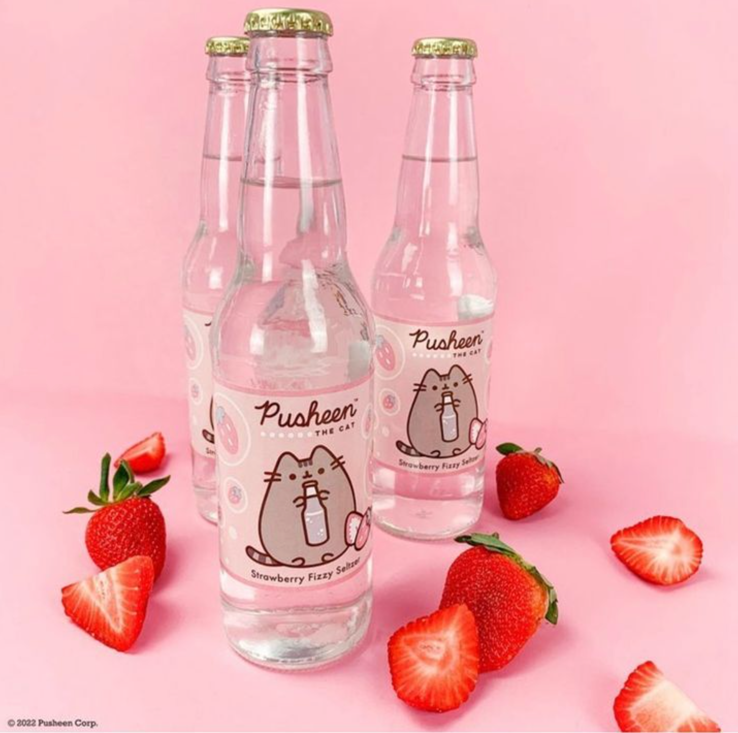 Four bottles of pusheen soda surrounded by strawberries