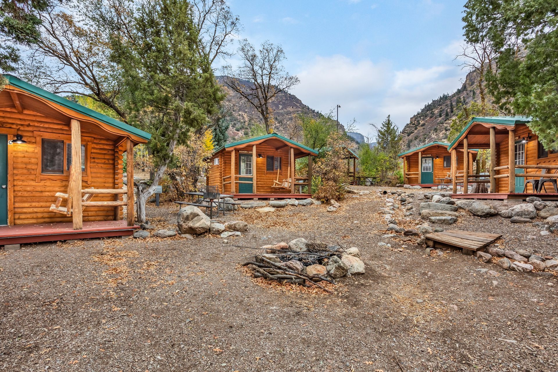 A group of wooden cabins are sitting next to each other in a dirt field.