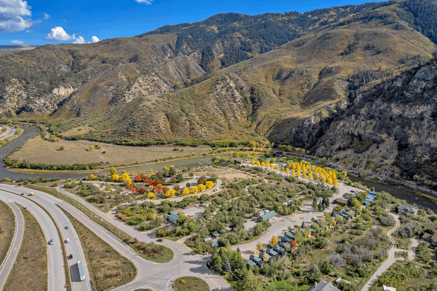 An aerial view of a campground surrounded by mountains and a river.