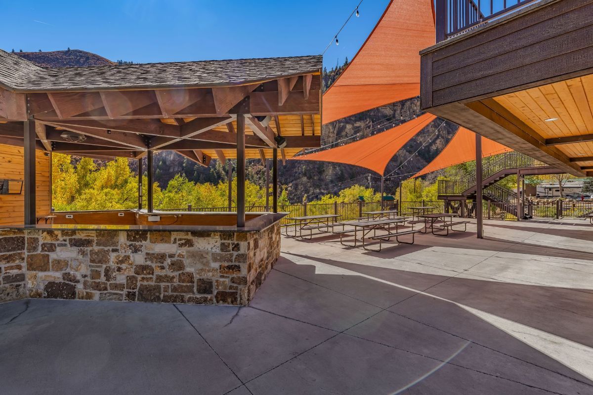 A patio with a stone wall , a bar and umbrellas.