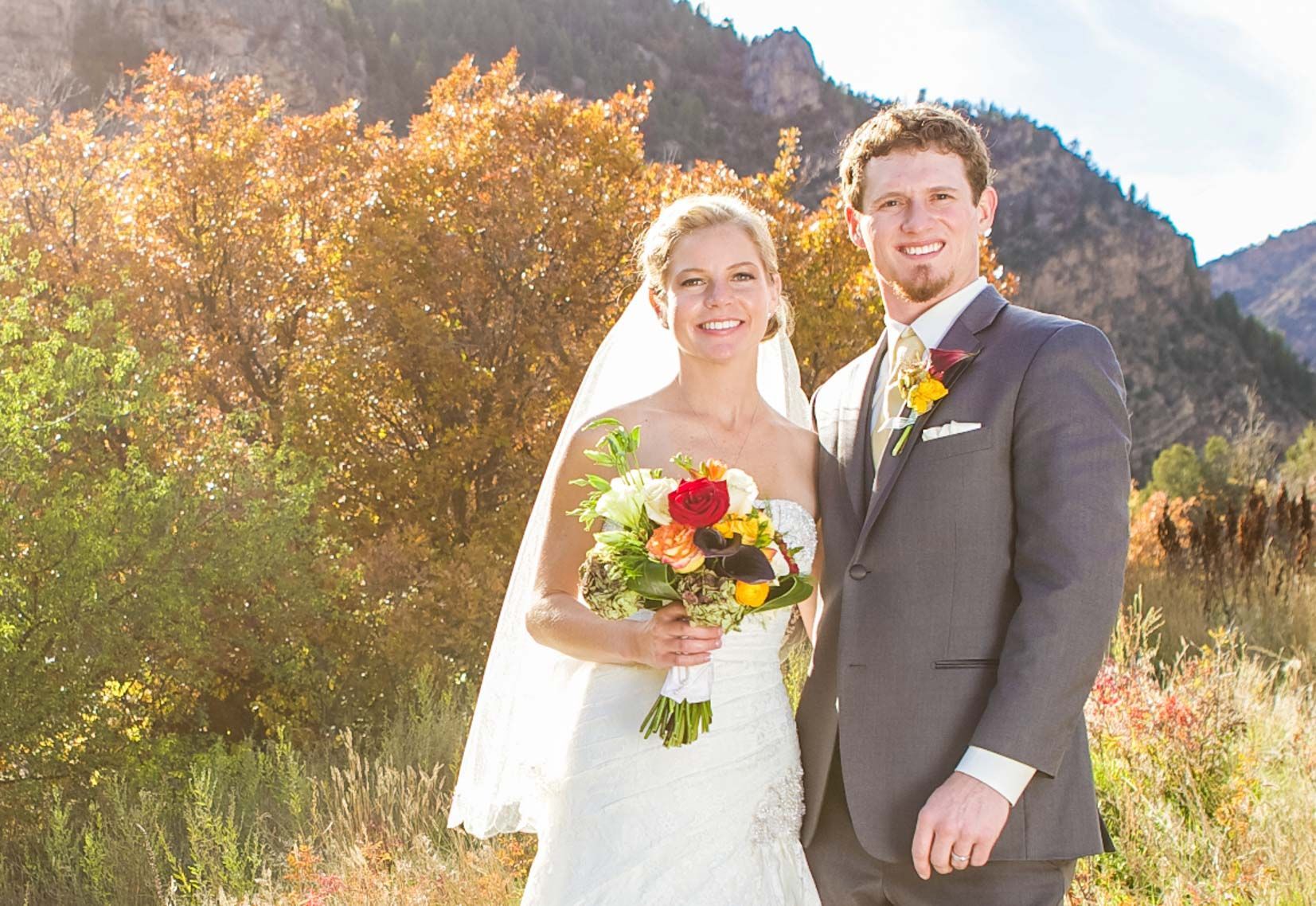 A bride and groom are posing for a picture in front of a mountain.