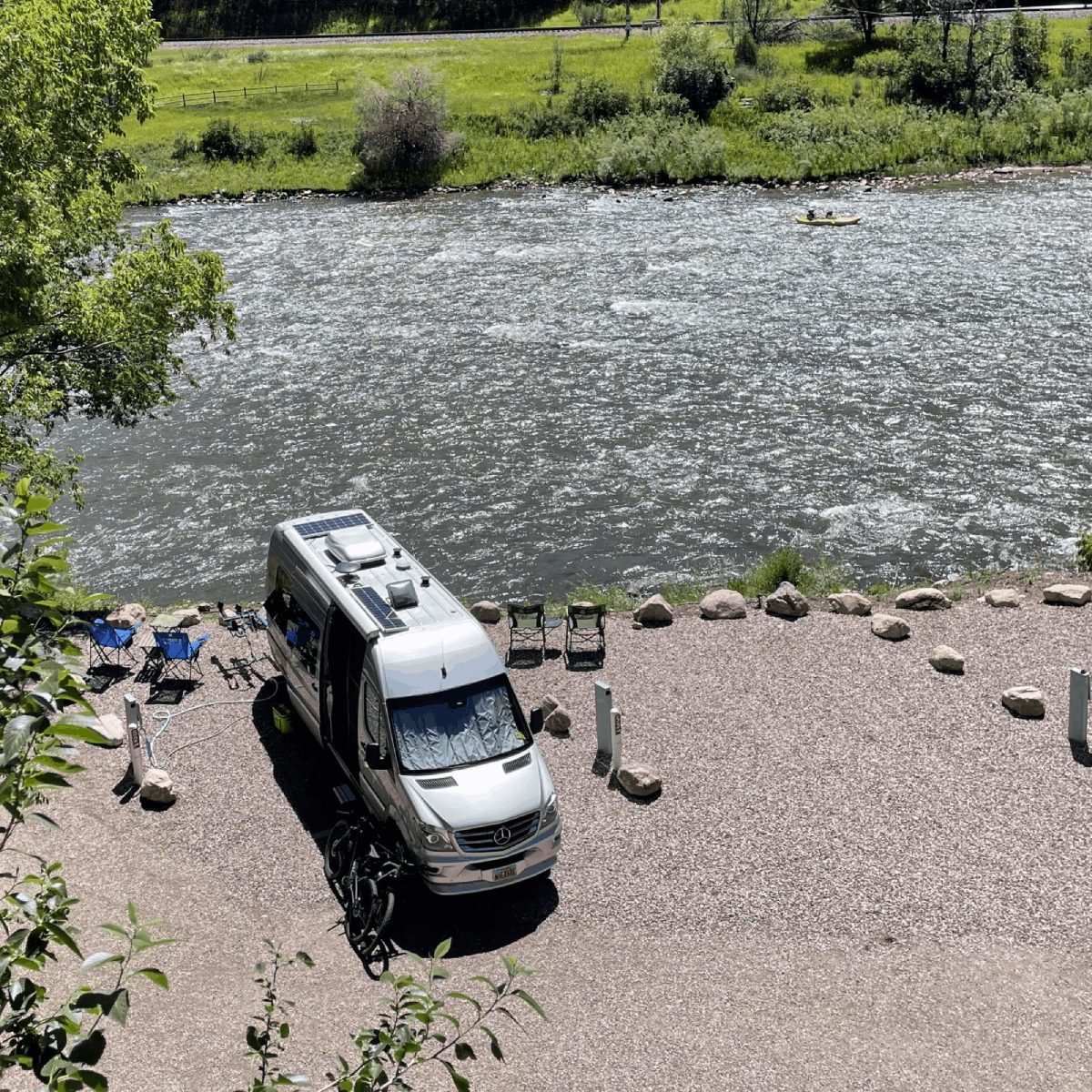 A white van is parked on the side of a river.