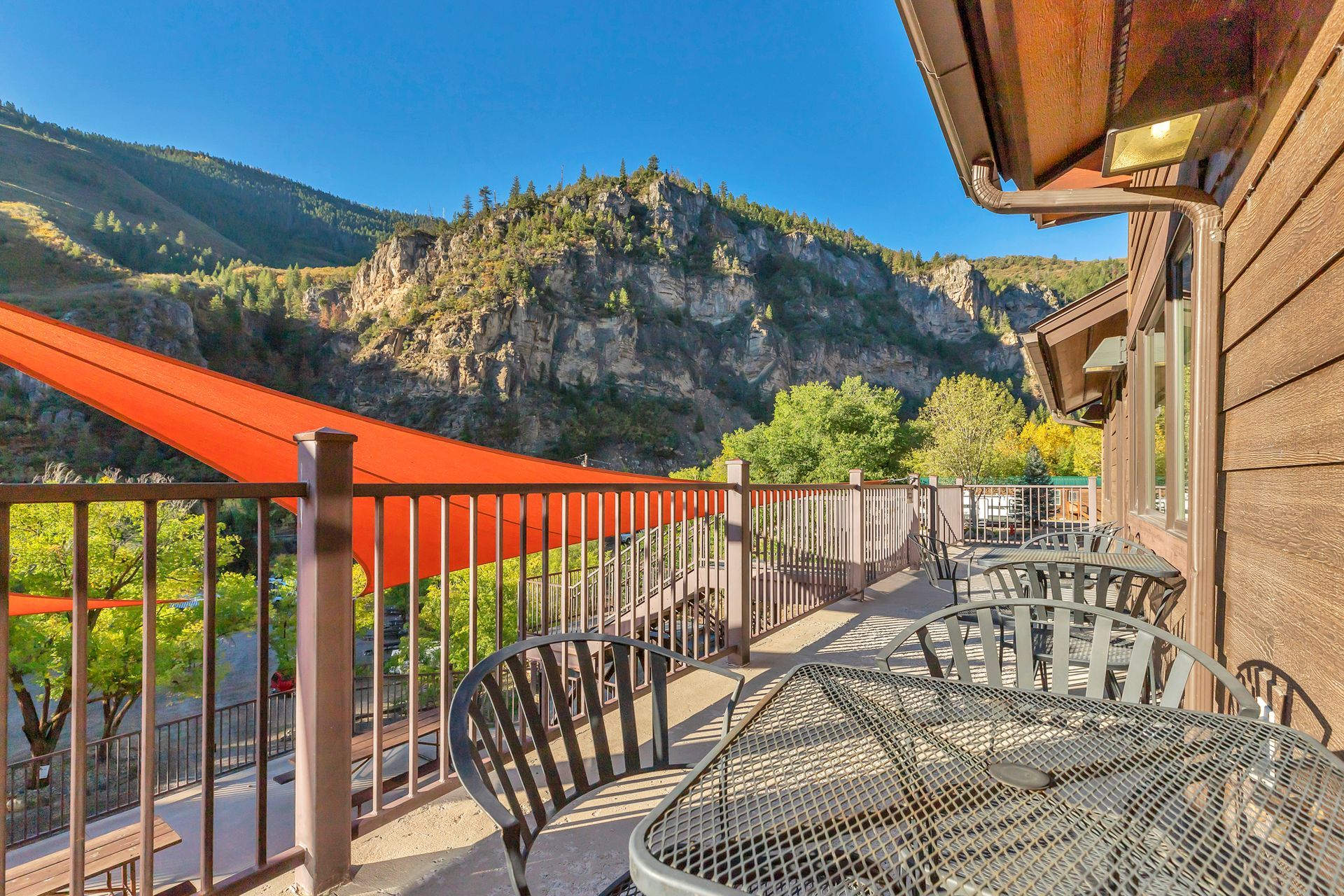 A balcony with a table and chairs overlooking a mountain range.