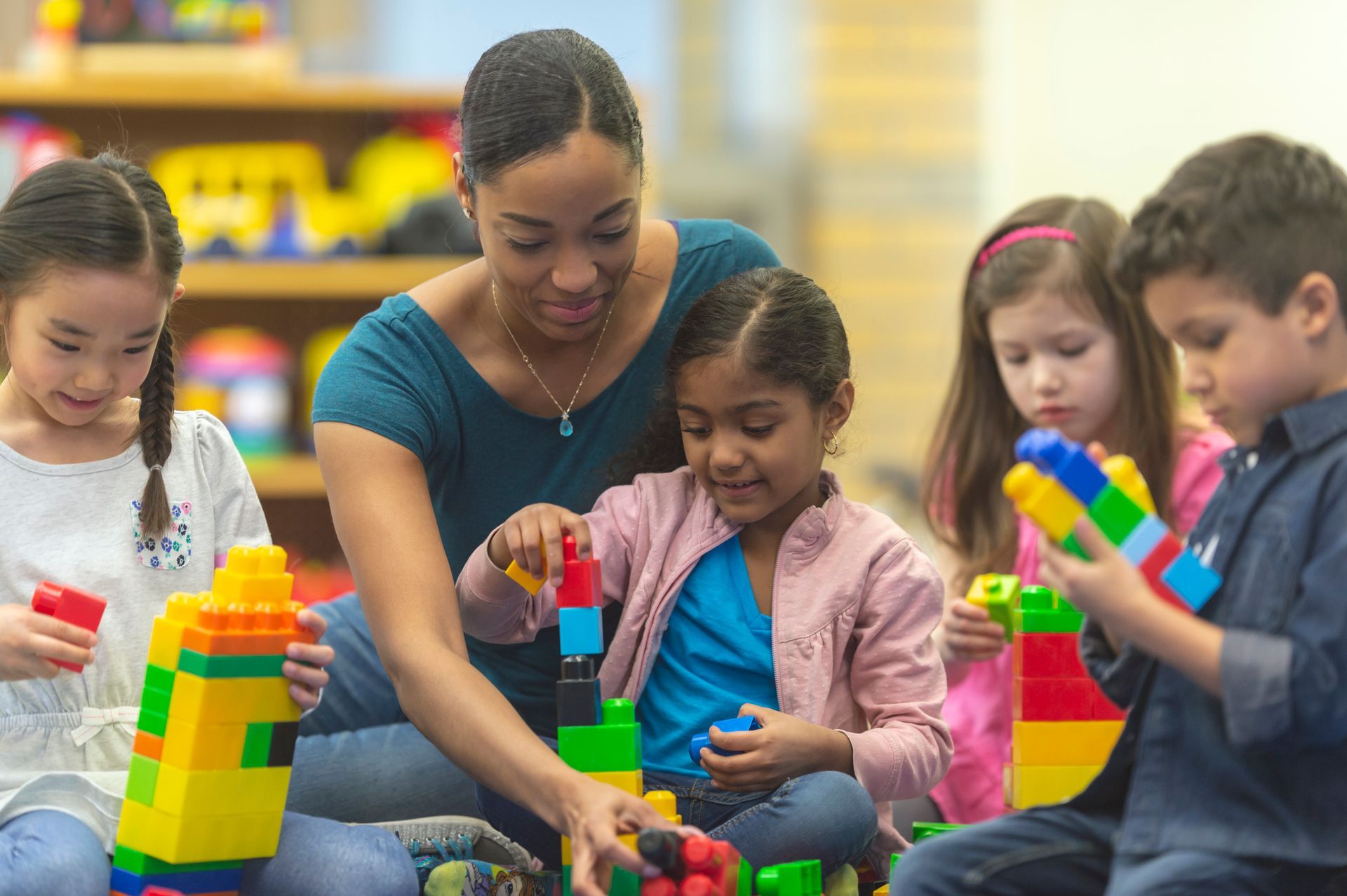 Picture of students and teacher playing with block toys in a kindergarten classroom
