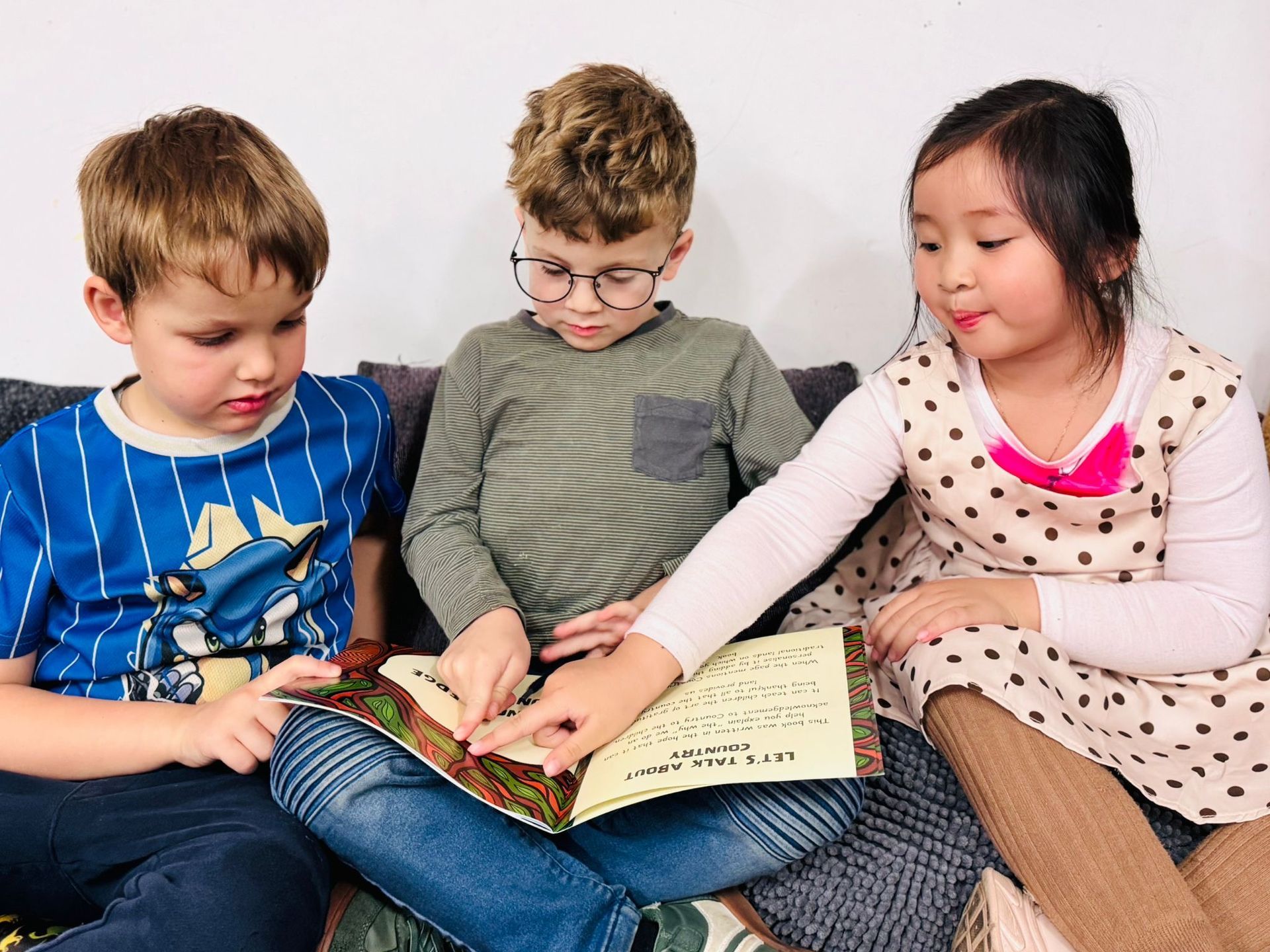 A father takes a photo of his two children, a boy and a girl, as they leave home for kindergarten.