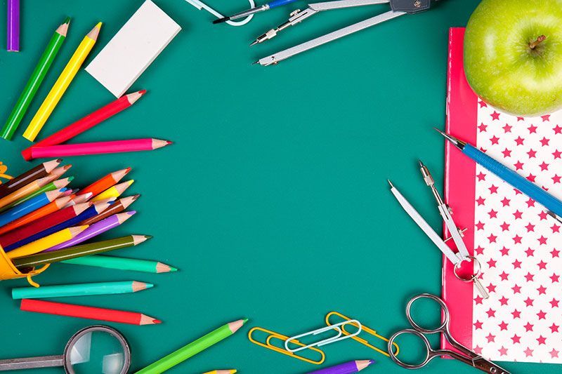 a green table topped with school supplies and an apple .
