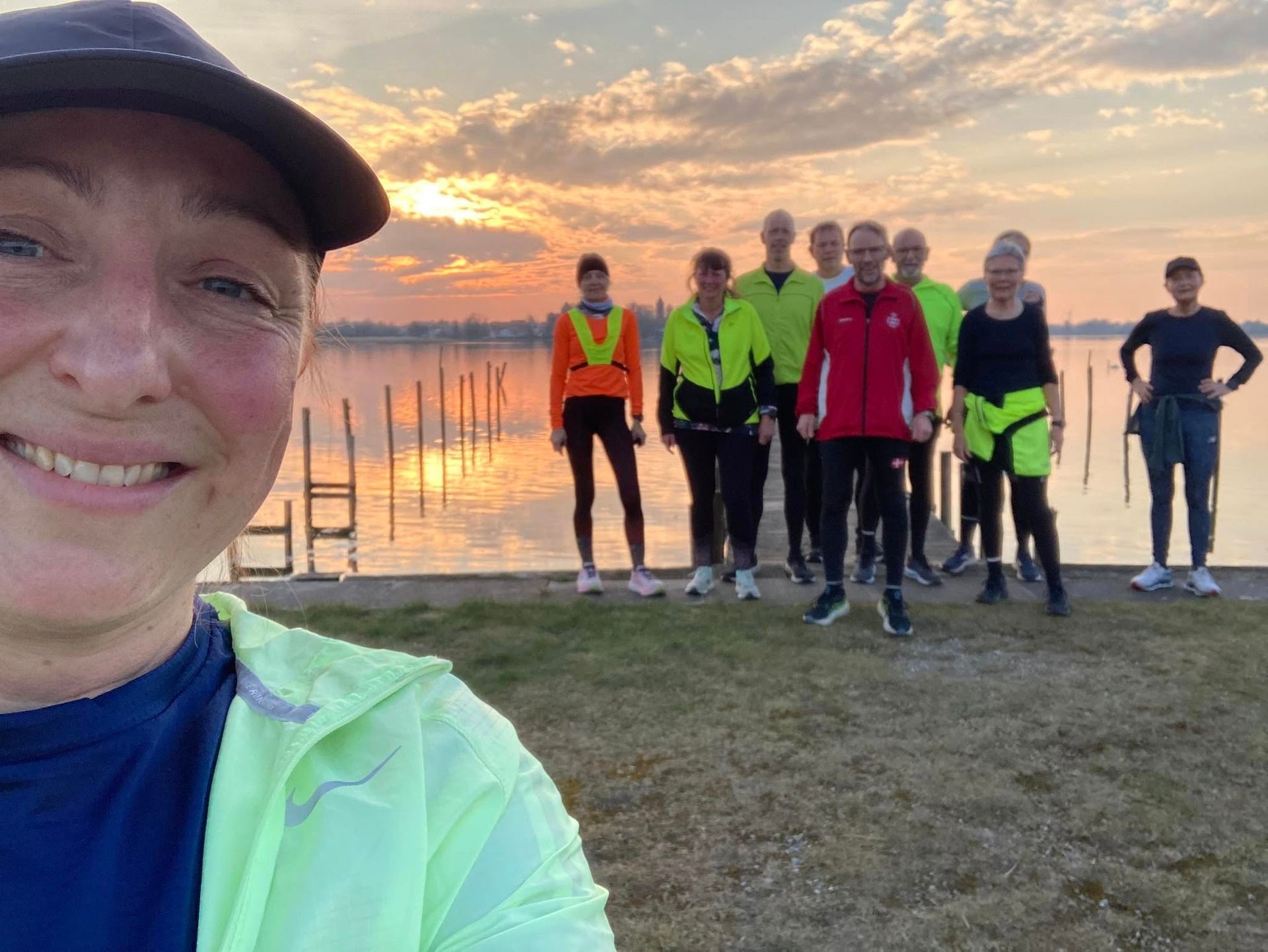 En kvinde tager en selfie med en gruppe mennesker, der står ved siden af ​​et vandløb.