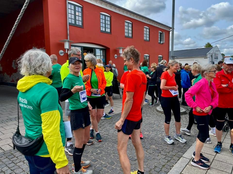 En gruppe mennesker står foran en rød bygning.