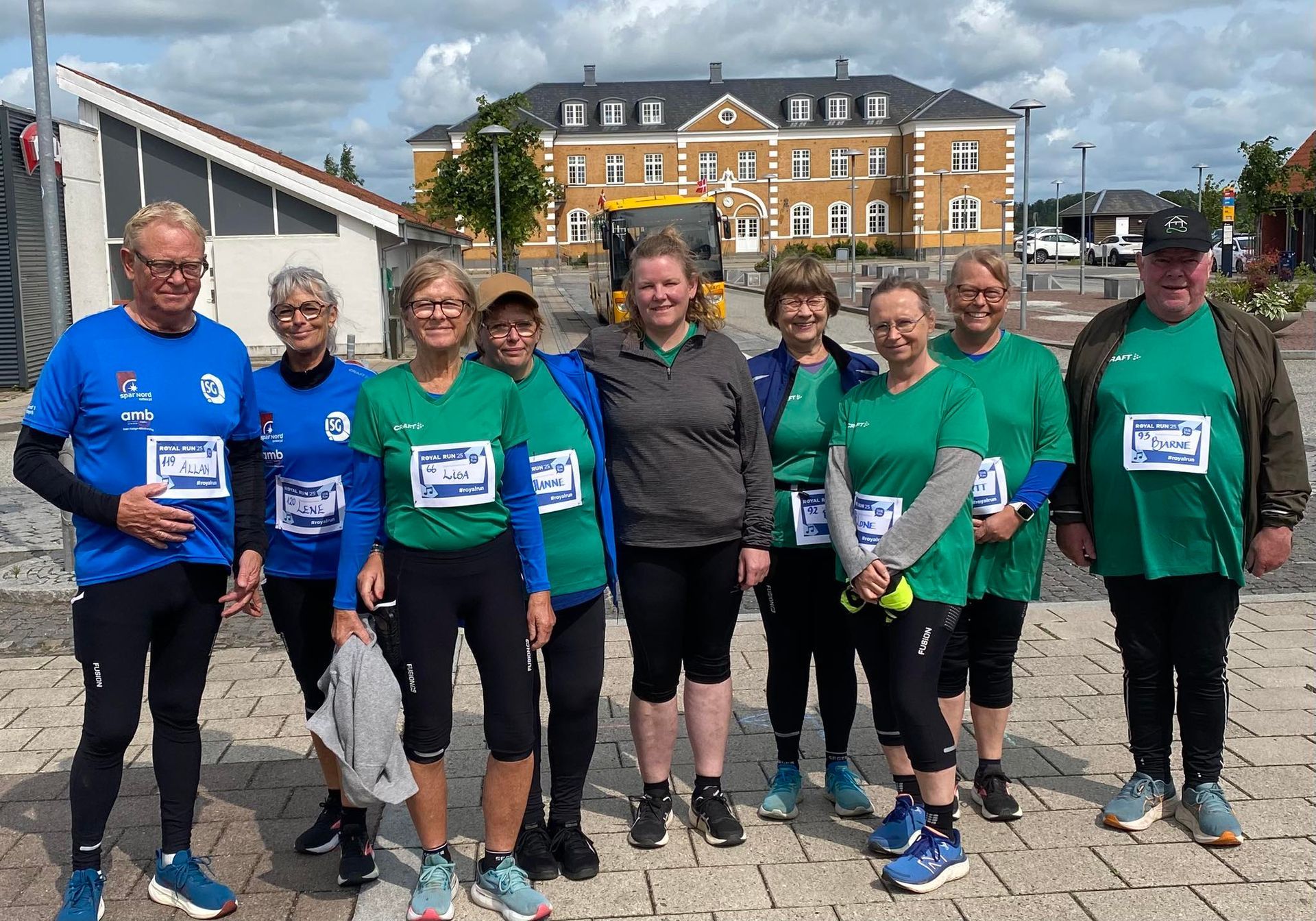 En gruppe mennesker poserer til et billede foran en bygning.