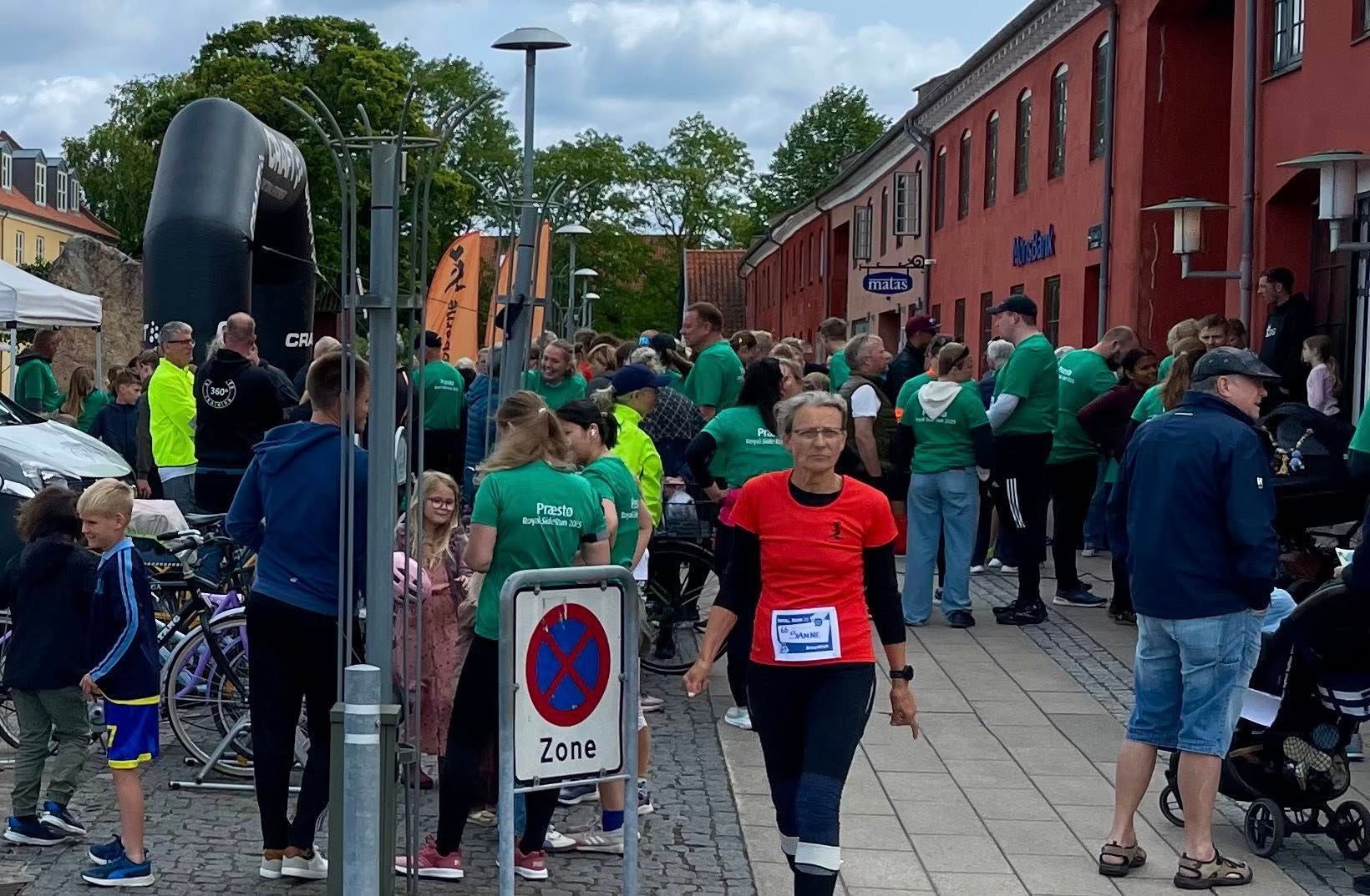 En gruppe mennesker går ned ad en gade foran et parkering forbudt-skilt.