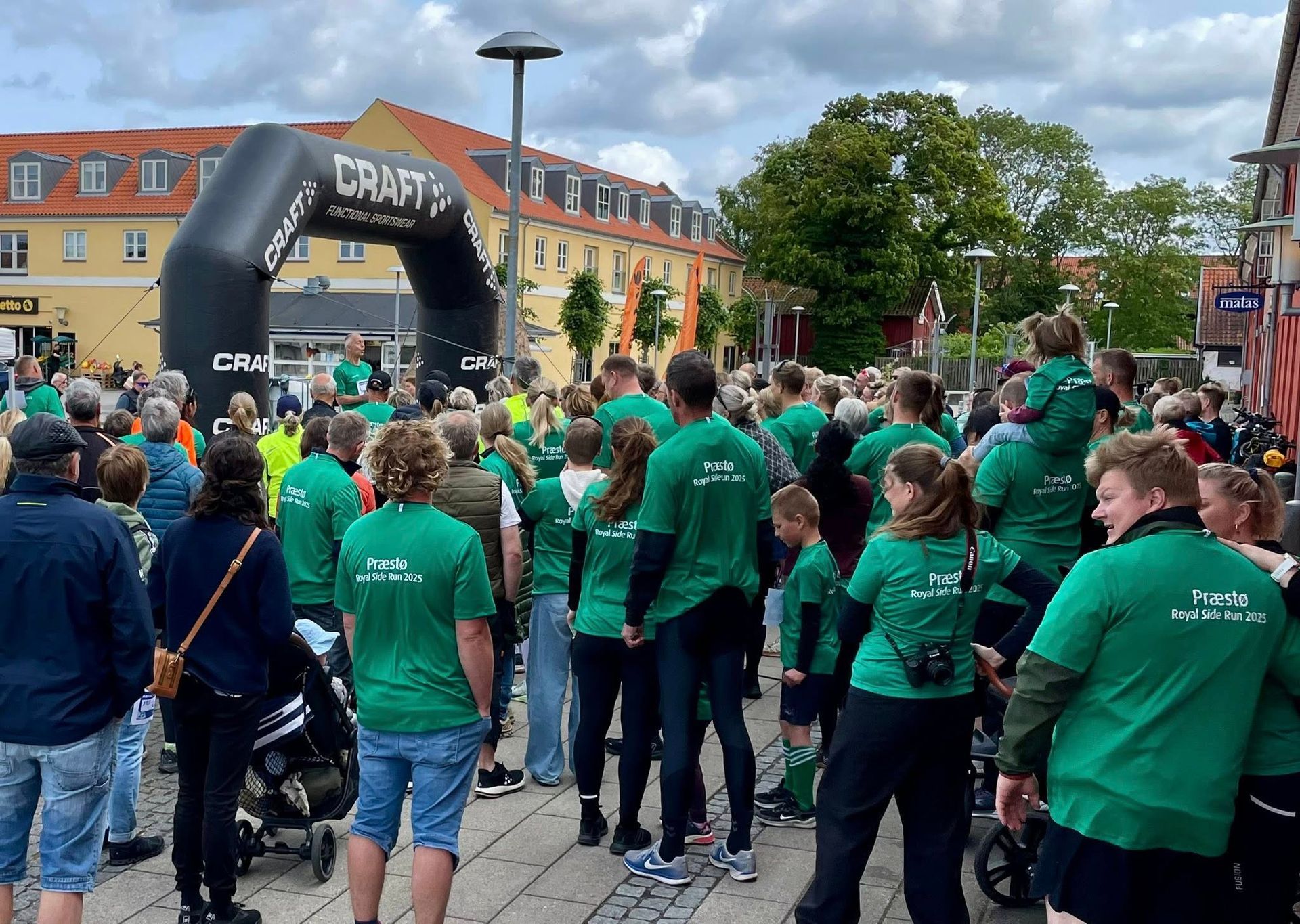 En gruppe mennesker iført grønne skjorter står foran en oppustelig håndværksbue.