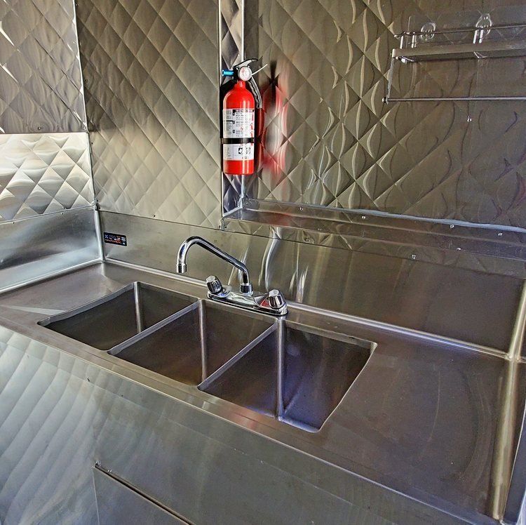 A stainless steel kitchen with two sinks and a fire extinguisher