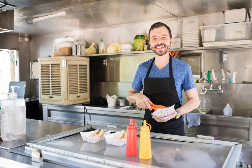 A man in an apron is preparing food in a food truck.