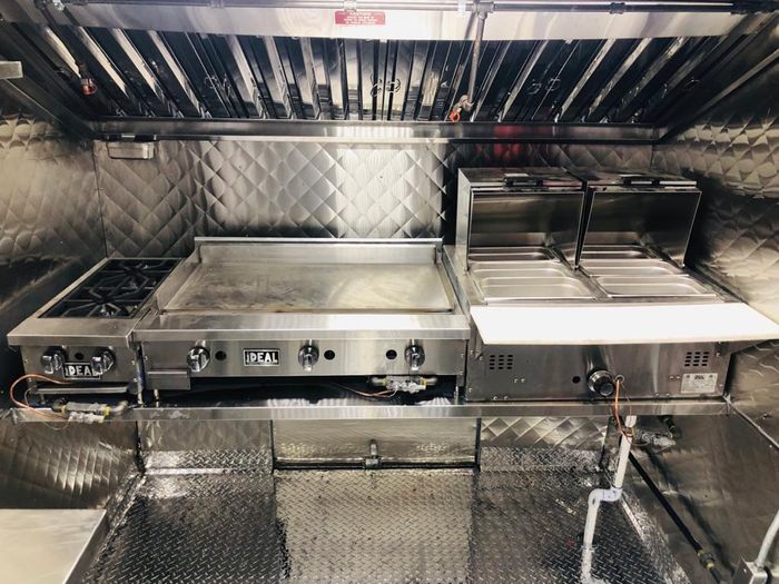 A kitchen with stainless steel appliances and a hood.