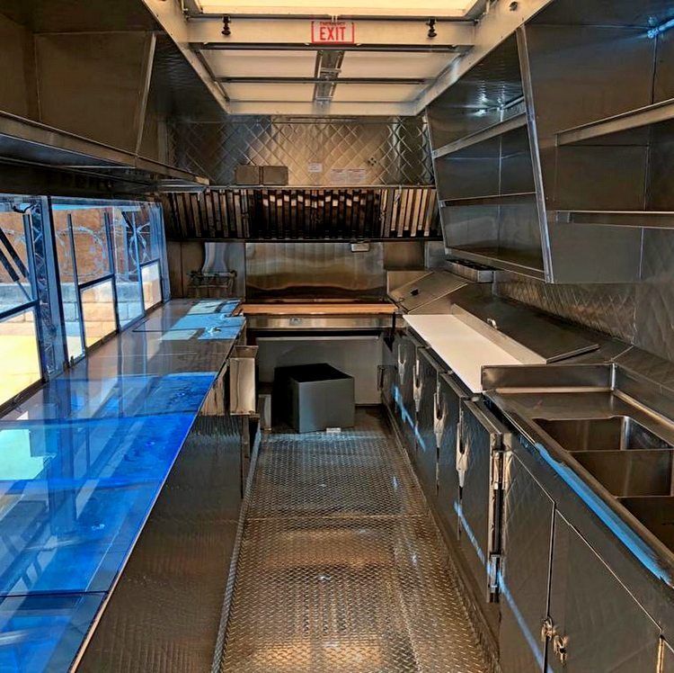 The inside of a food truck with a lot of stainless steel appliances.
