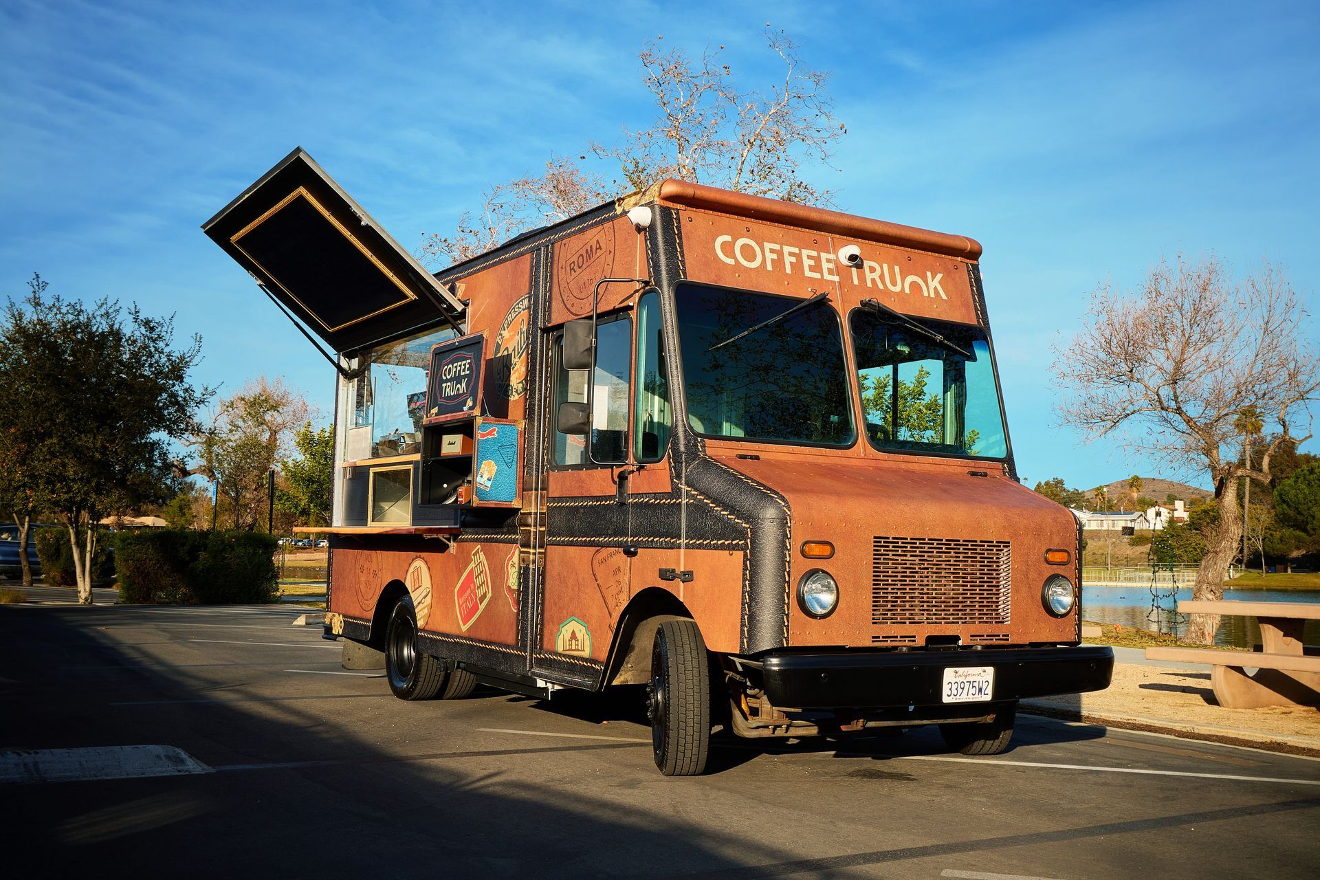 Coffee truck with open service window parked outdoors on sunny day.