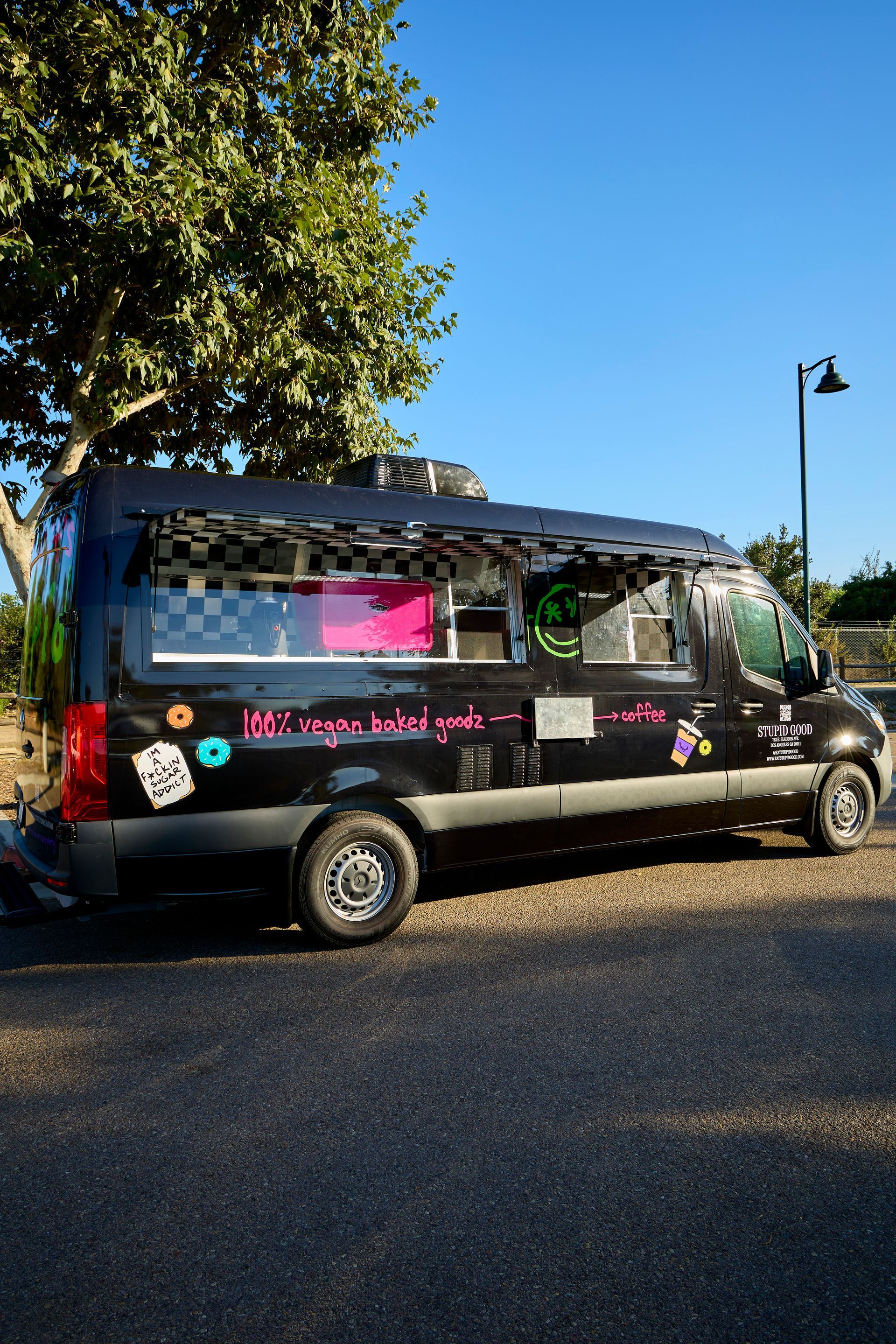 Black food truck with pink and checkered accents parked on asphalt.