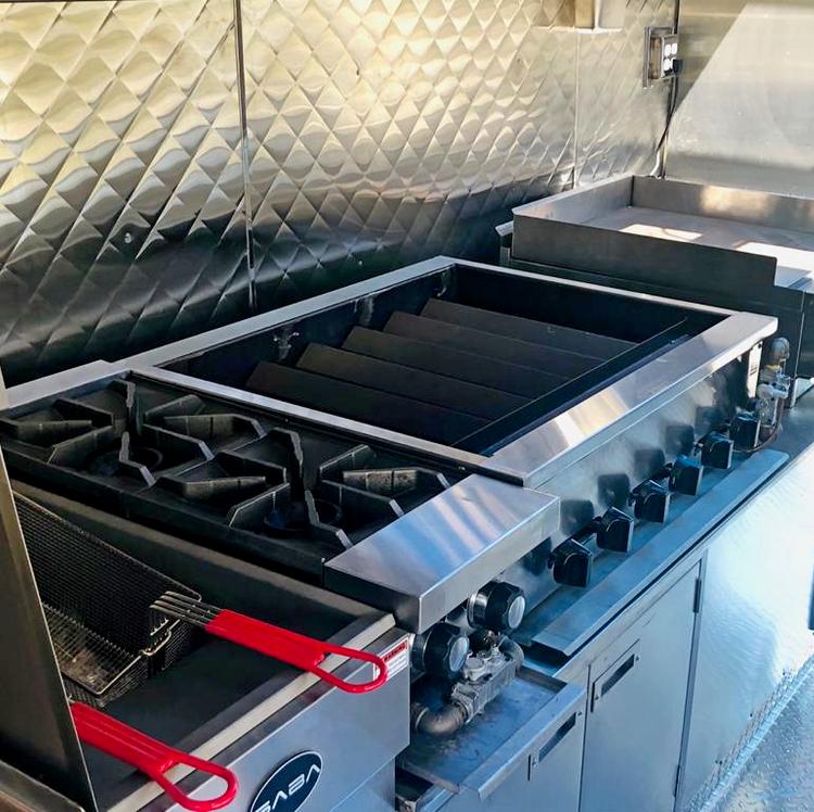 A stainless steel stove with a fryer and tongs on it