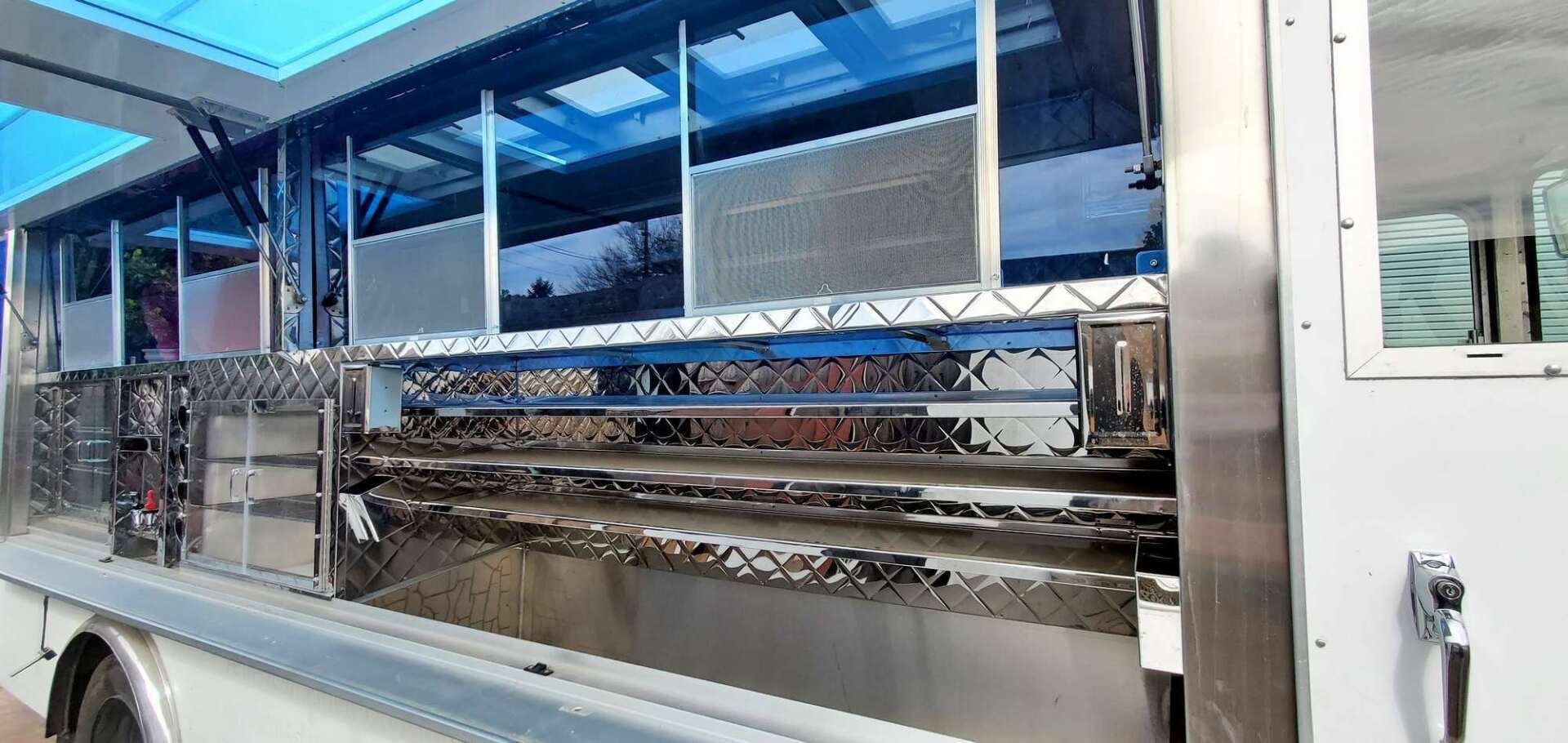 The inside of a stainless steel food truck with a window.