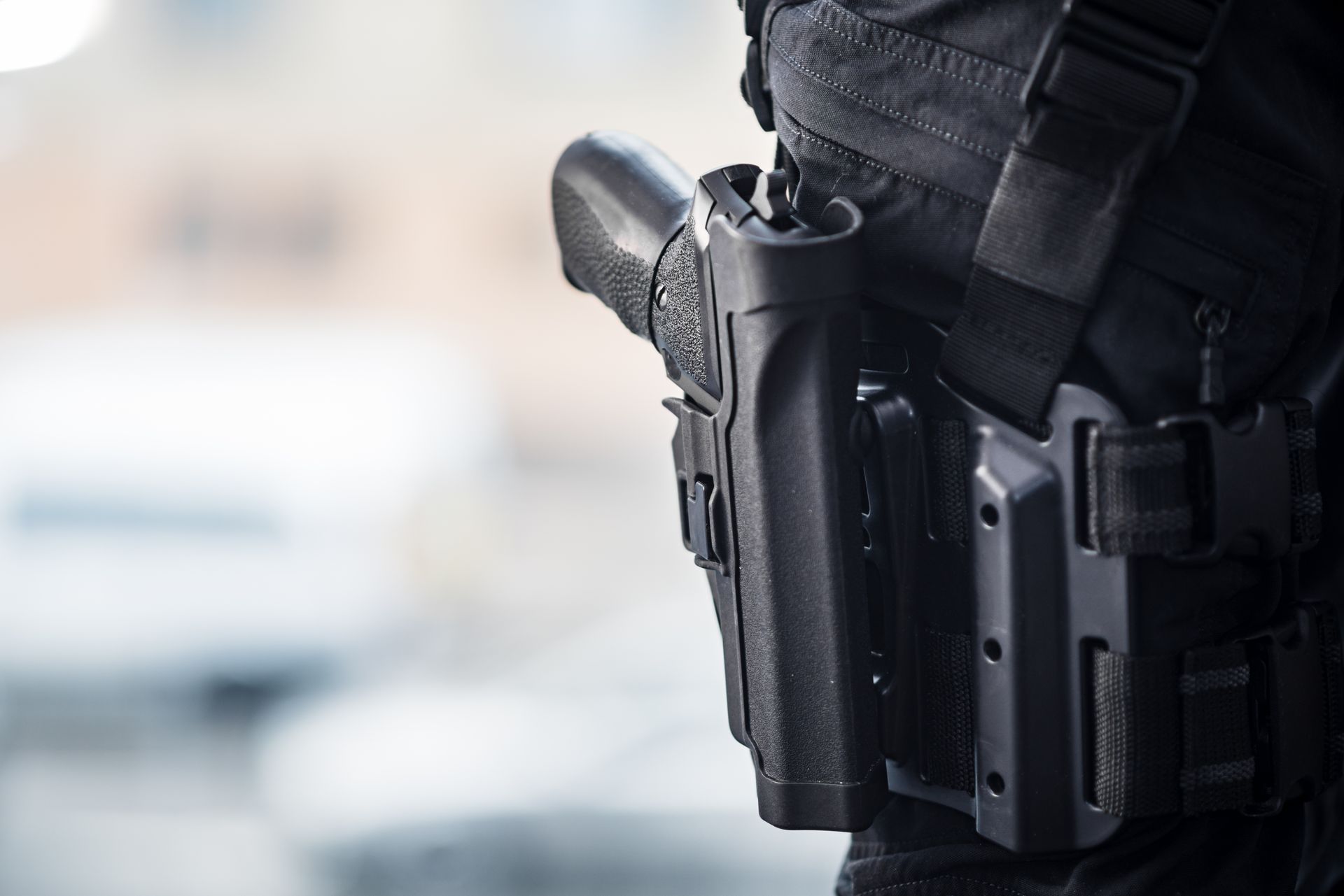A security guard’s holstered firearm is shown on a duty belt during patrol.