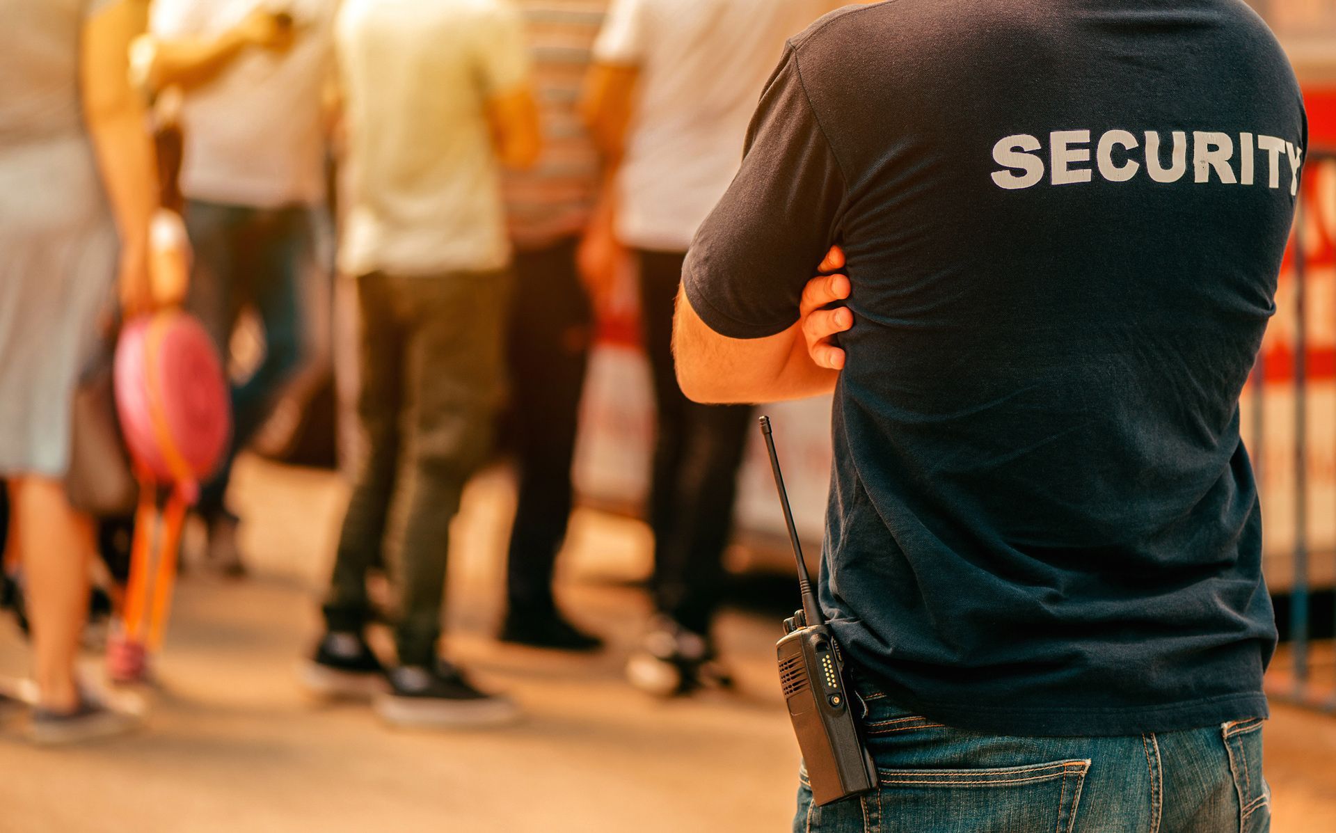 A security guard is standing in front of a crowd of people.