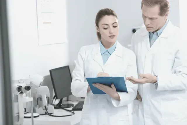 A man and a woman are looking at a clipboard in a laboratory.
