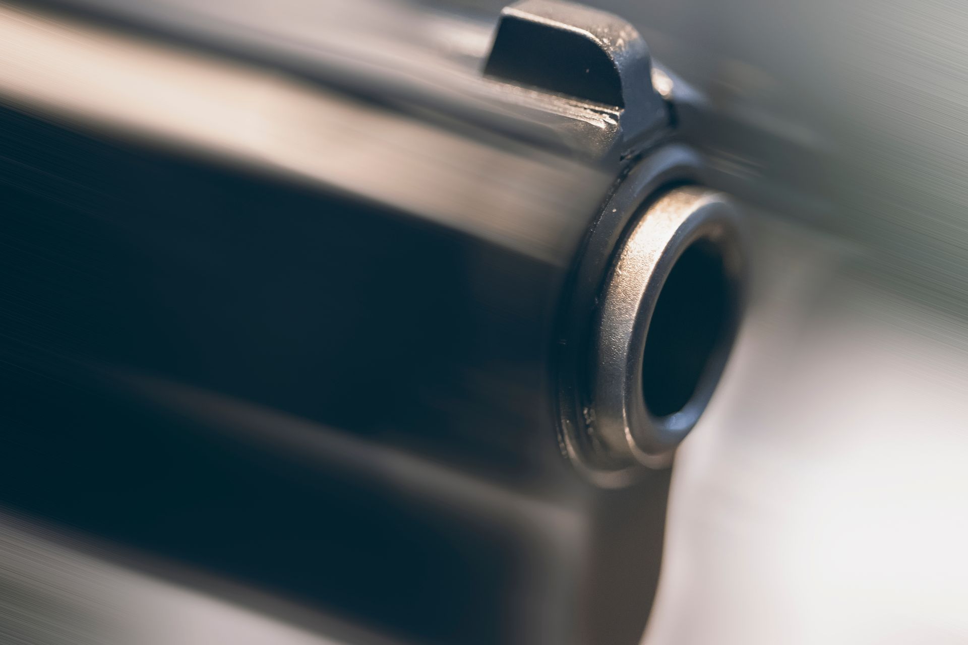 Close-up of a gun barrel, dark metallic with a focus on the opening.